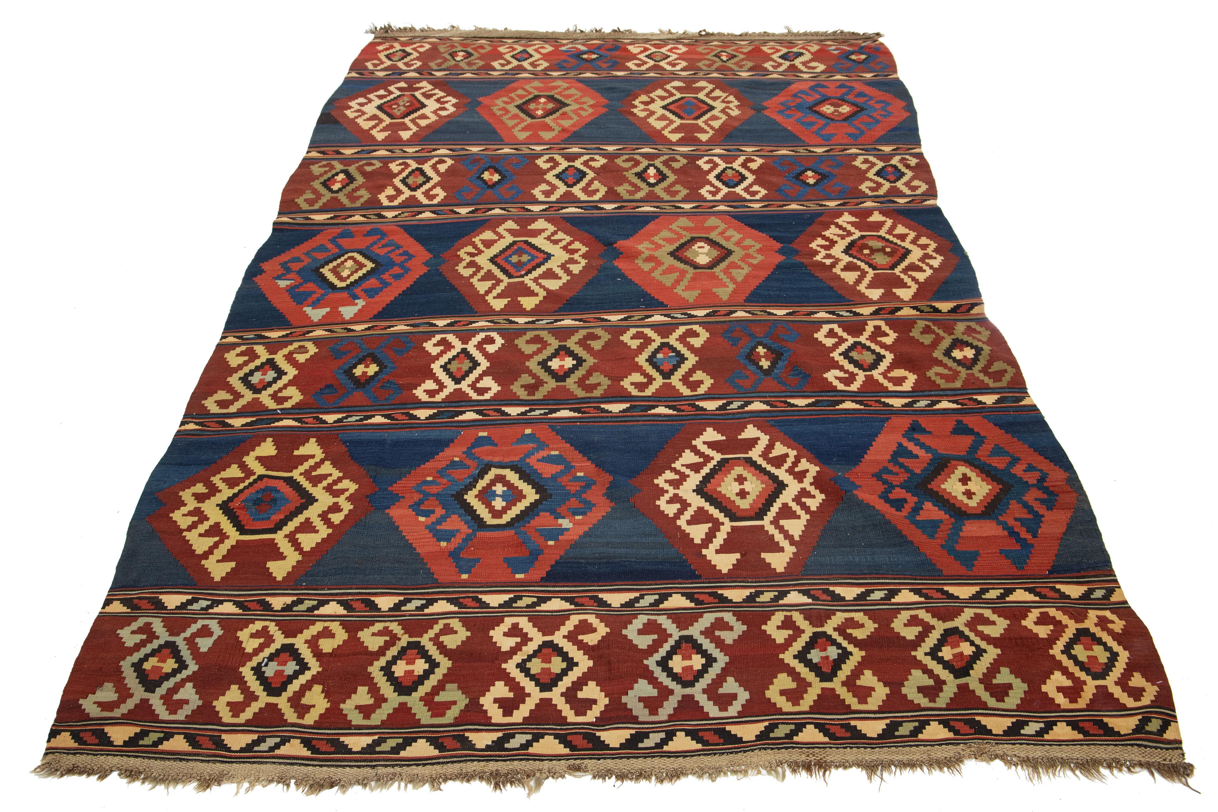 Introducing a beautiful vintage kilim wool rug, meticulously hand-knotted with a captivating geometric design in rust and beige against a striking blue backdrop.

This rug measures 6' x 10'2