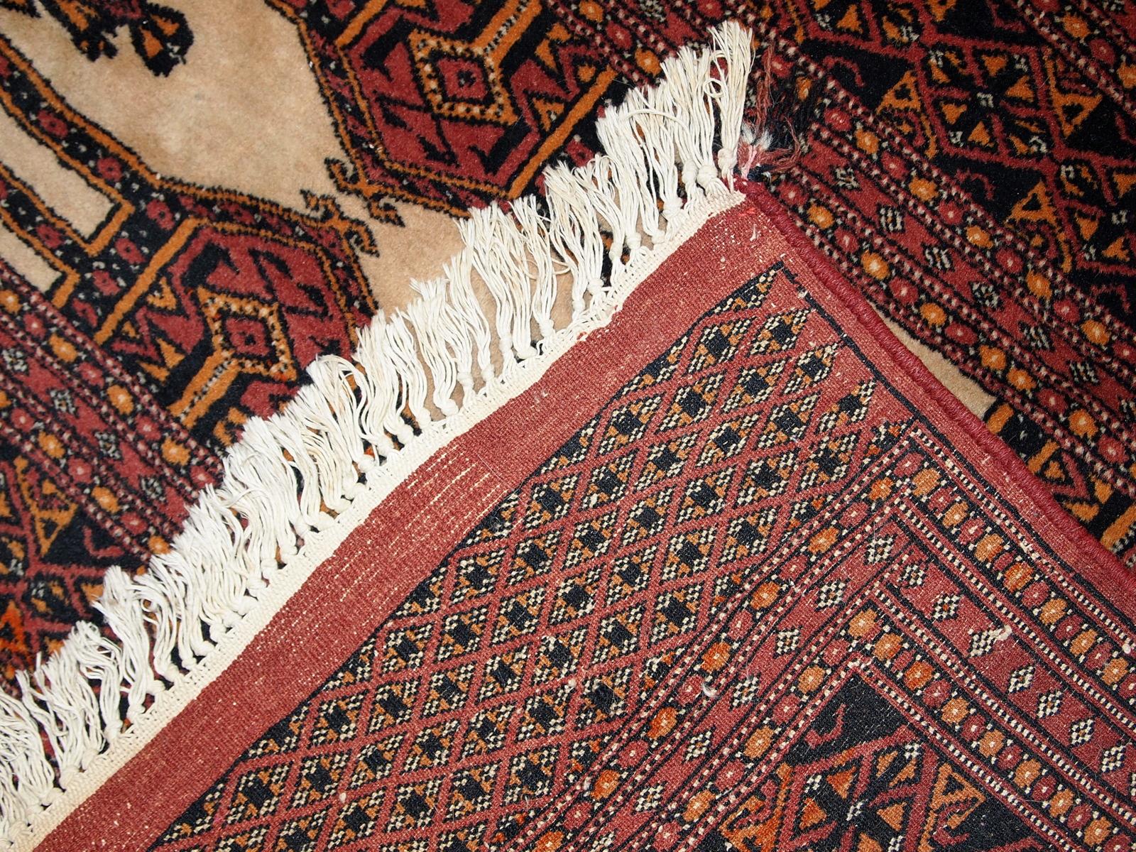 Handmade semi-antique Turkoman rug with beige field and red border. Orange color accented on tribal figures. The pile on this rug is thick, soft and comfortable. 

- Condition: original good,

- circa 1950s,

- Size: 2.8' x 4' ( 87cm x 123cm