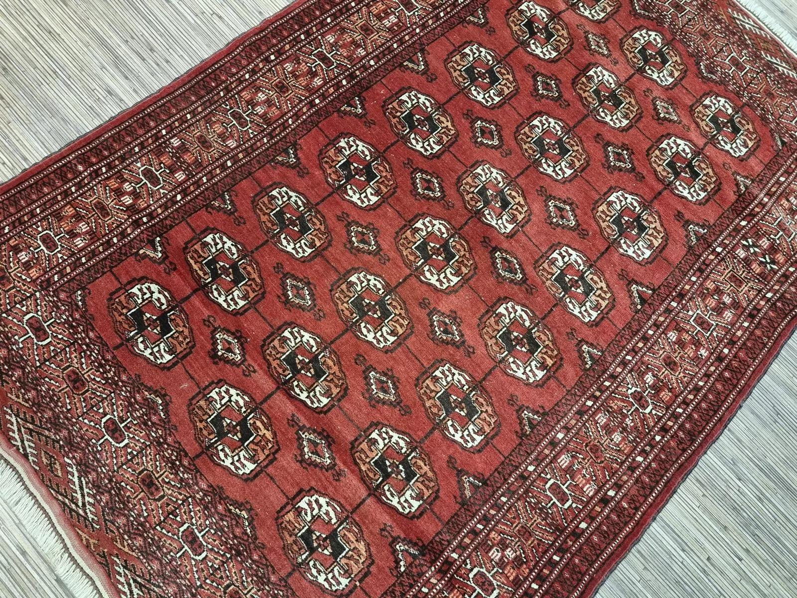 Questo tappeto Tekke vintage degli anni '50 è uno squisito esempio di artigianato tradizionale. Con una lunghezza di 180 cm e una larghezza di 121 cm, questo bellissimo tappeto in lana è in buone condizioni e presenta un ricco e intricato disegno