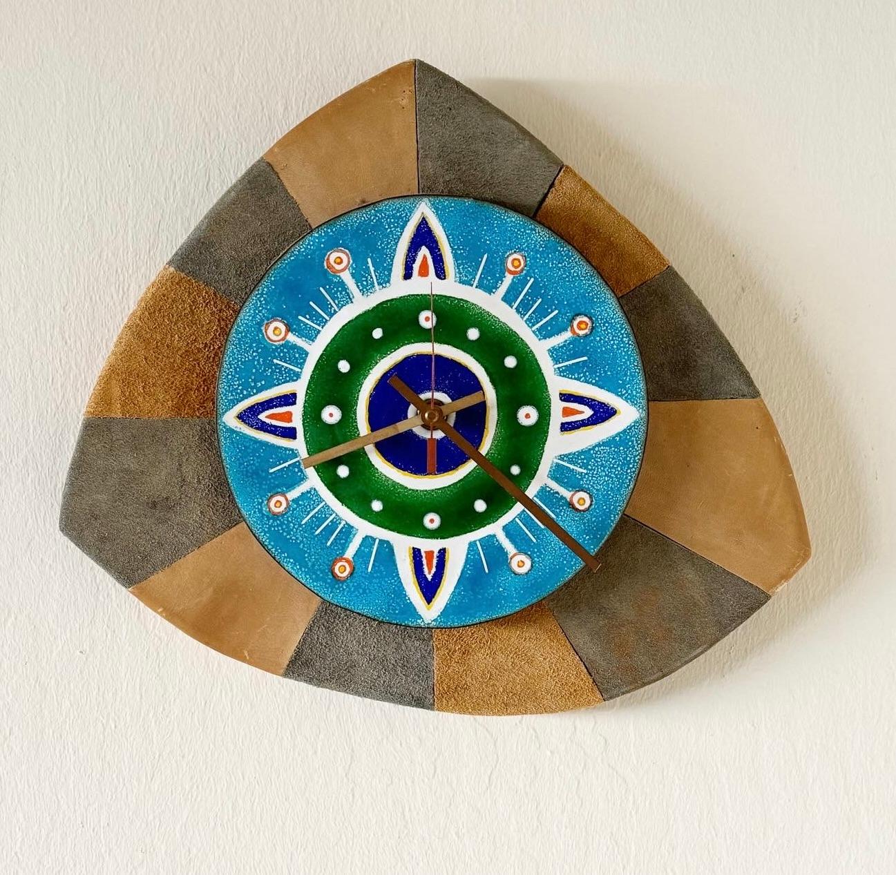 Late 1970s one of a kind handmade wall clock, constructed of a radius of earth toned suede on a solid asymmetrical wooden frame. The clock face is an abstract enameled copper in blue, white, orange and green with copper minute, hour and second