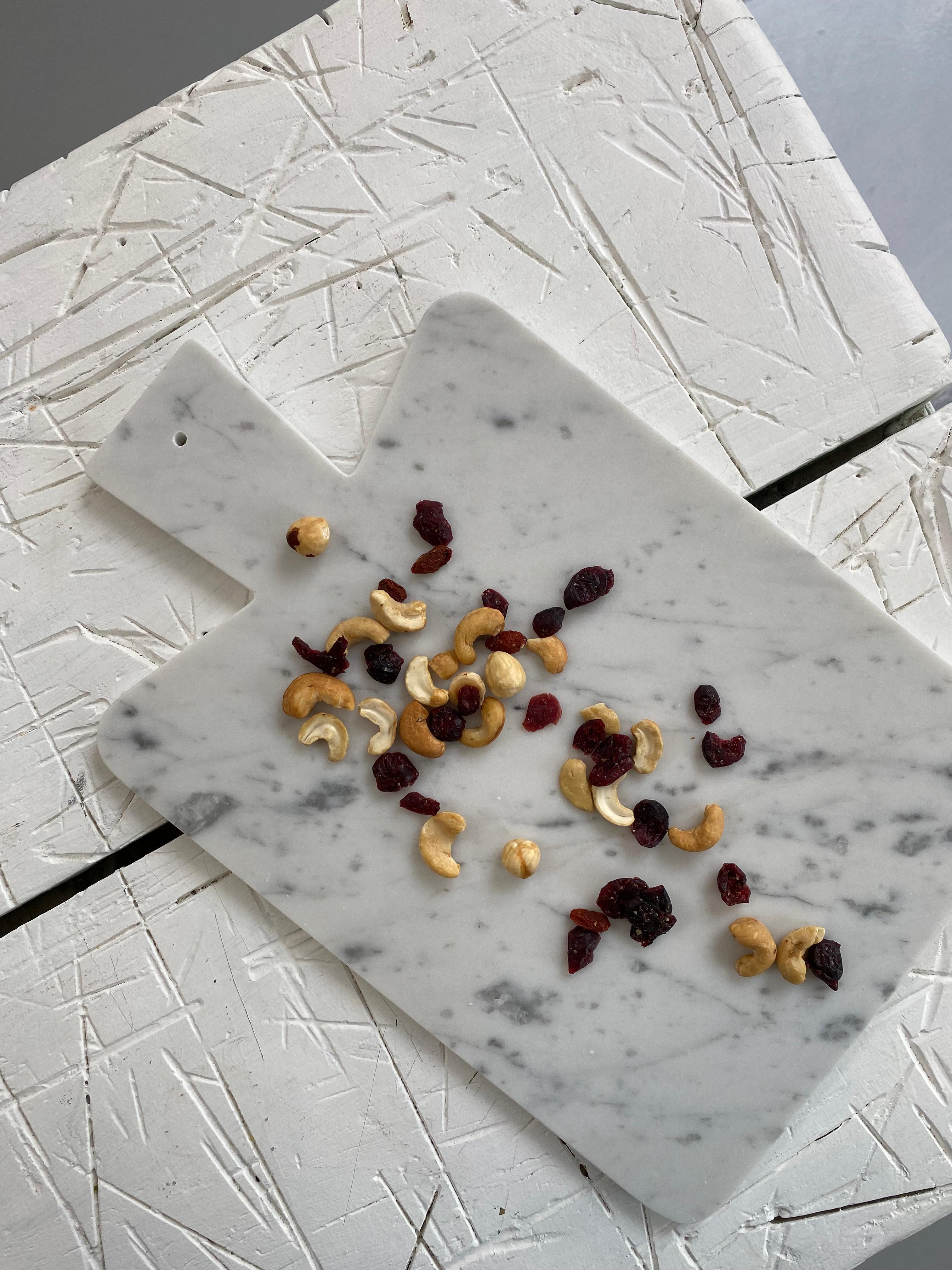 White Carrara marble cutting board and hole on the handle to hang it. Each piece is in a way unique (every marble block is different in veins and shades) and handmade by Italian artisans specialized over generations in processing marble. Slight