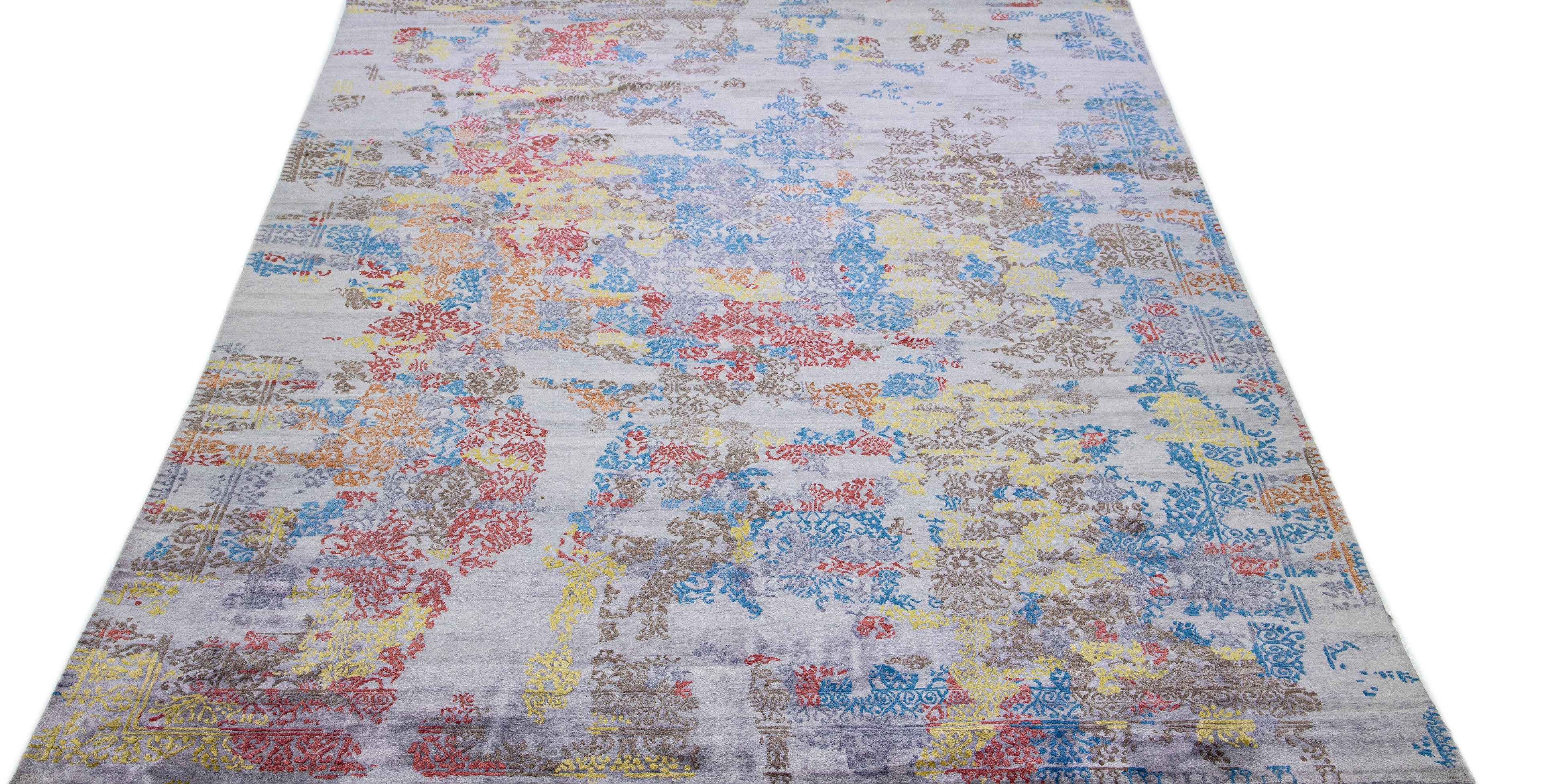 Dieser indische Teppich aus einer Mischung aus Wolle und Seide zeigt ein graues Feld mit einem abstrakten Muster in leuchtenden Farben. Seine komponierten Materialien sorgen für Robustheit und Langlebigkeit, während sein ornamentales Design jeden