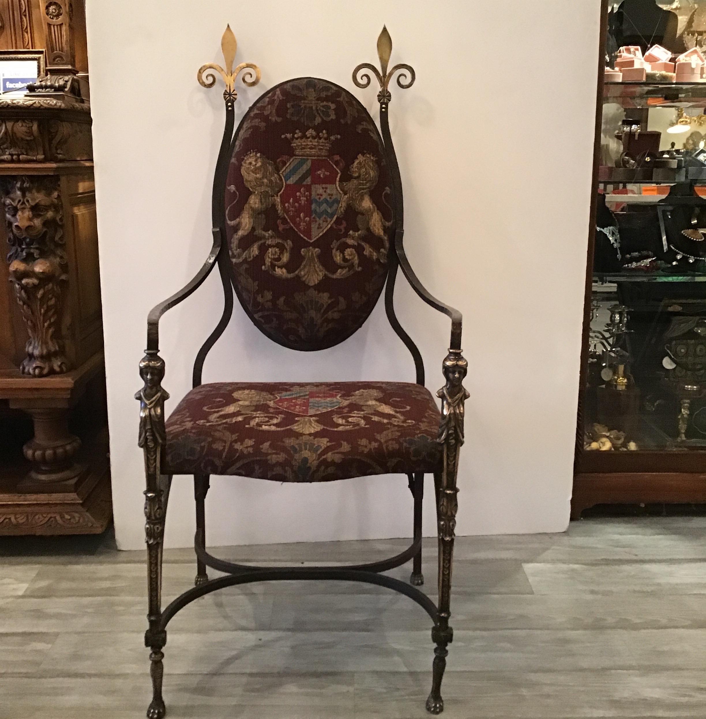 Handsome hand forged wrought iron and burnished brass chair with printed sturdy weight armorial fabric. The frame is solid hand forged iron with brass fleur-de-lis finials and cast brass figurative fronts and feet. The oval back and seat covered in
