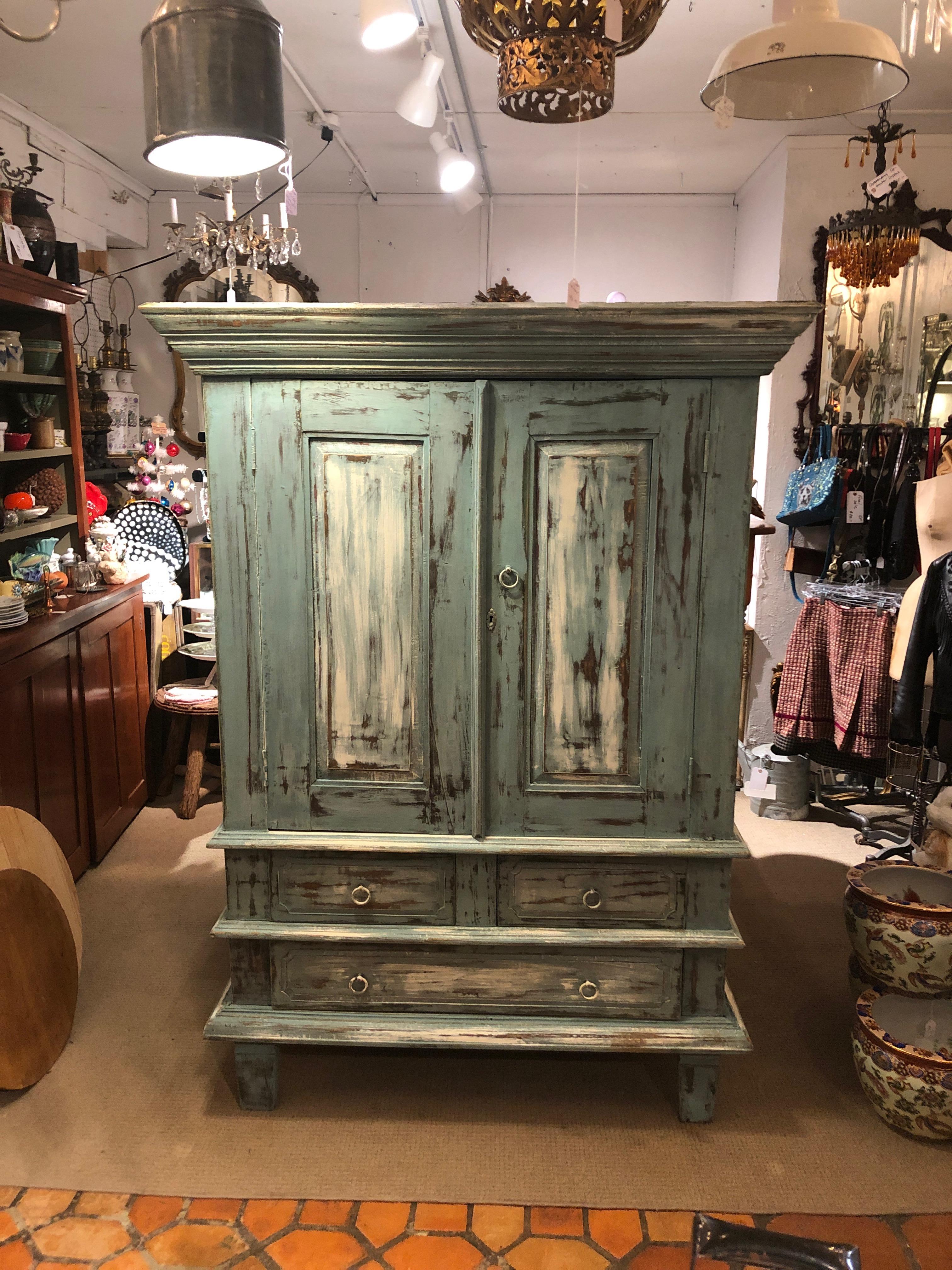 Wonderful and very functional distressed painted cabinet having paneled doors that open to reveal space for clothes, shoes, entertainment center, blankets, etc. There are two medium sized drawers below and one large drawer. The colors are a soft