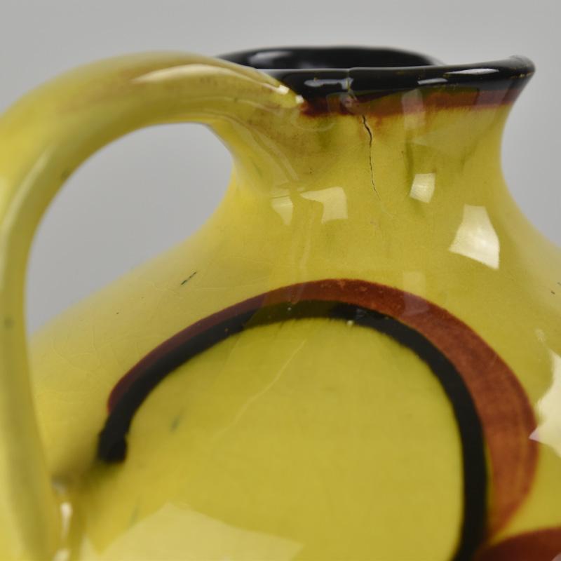 Questo vaso vintage unico, dipinto a mano, presenta un sorprendente design Bauhaus in stile Art Déco con forti motivi di ispirazione suprematista. Realizzato in Germania intorno al 1920, questo pezzo modernista presenta uno smalto giallo vivo con