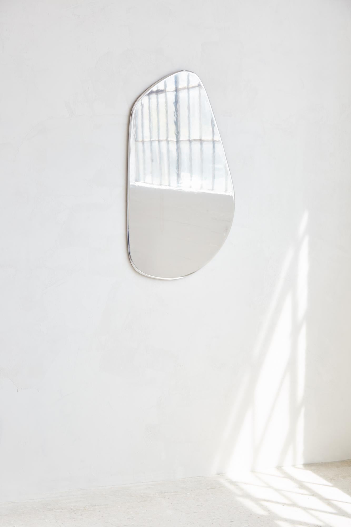 MIROIR GÉOMORPHE
Le miroir Geomorph constitue une rupture visuelle avec le reste de l'ameublement, reprenant la même inspiration en matière de design sans aucun élément en bois visible. Fabriqué en aluminium poli plutôt qu'en verre, le miroir