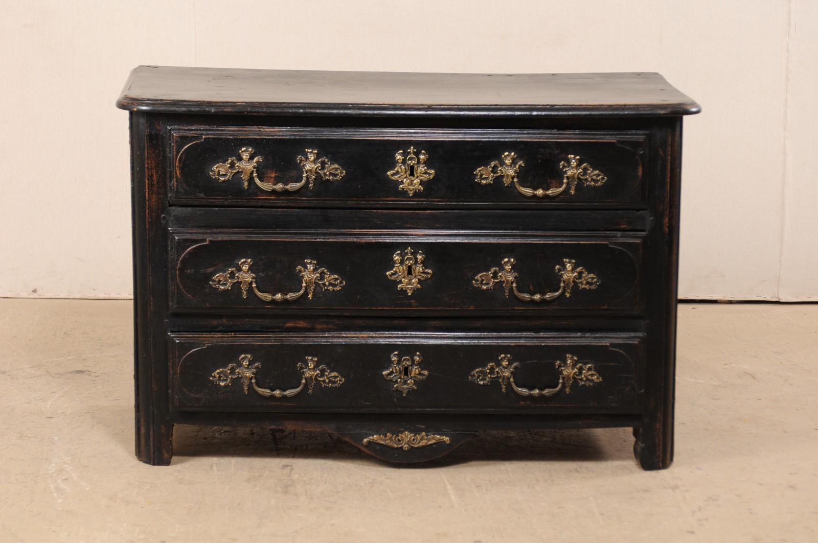 An 18th century French three-drawer wood chest. This antique chest from France has a rectangular-shaped top with curved front corners, which slightly overhands the case below which houses three full-sized, graduated doors. Drawers are flanked with