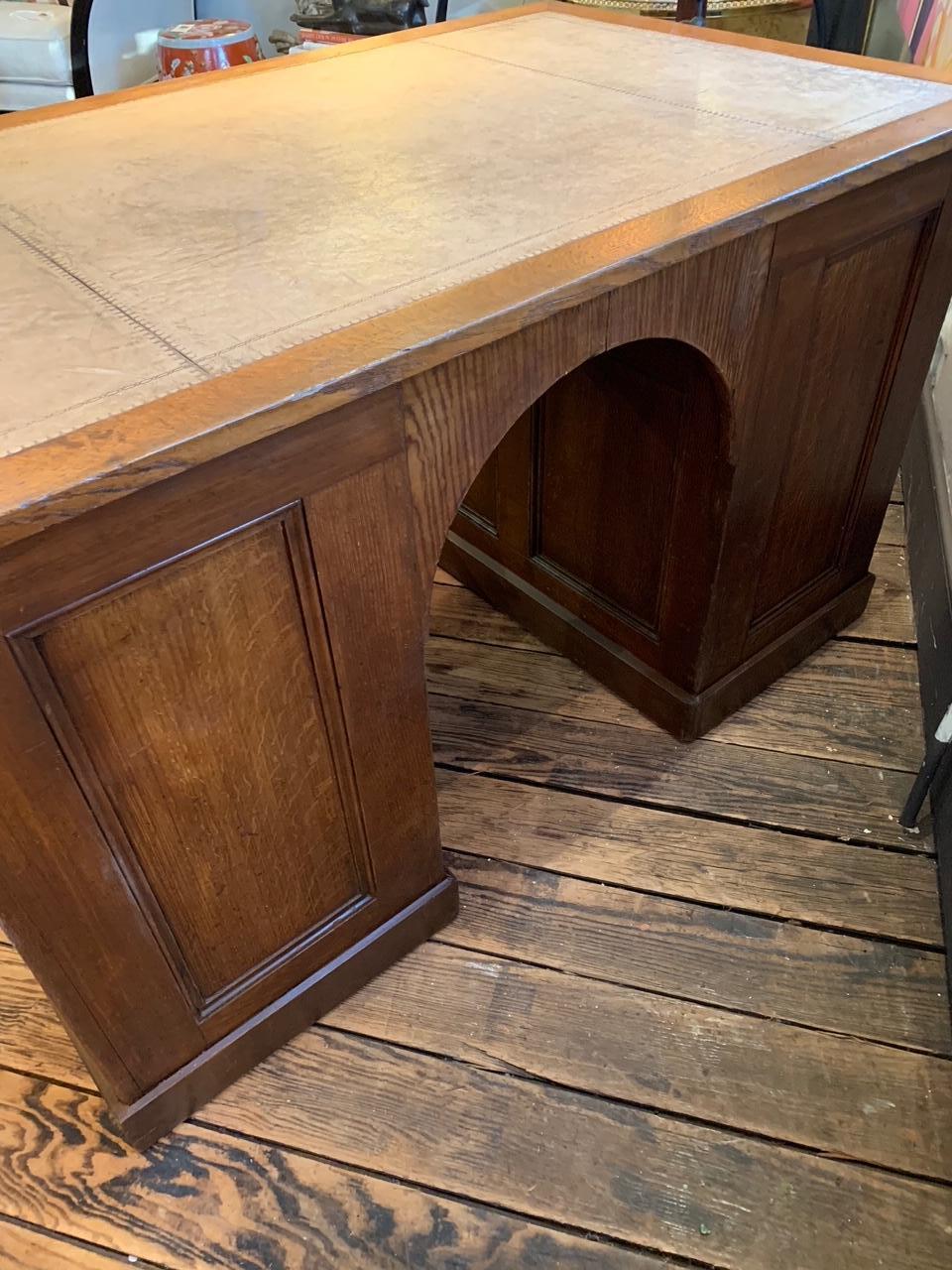 Handsome English double pedestal desk with grain painted, paneled sides, arched front, and 4 drawers in each pedestal on one side. Tooled light tan leather top in good condition.
From the estate of a prominent New England decorator.

Measures: