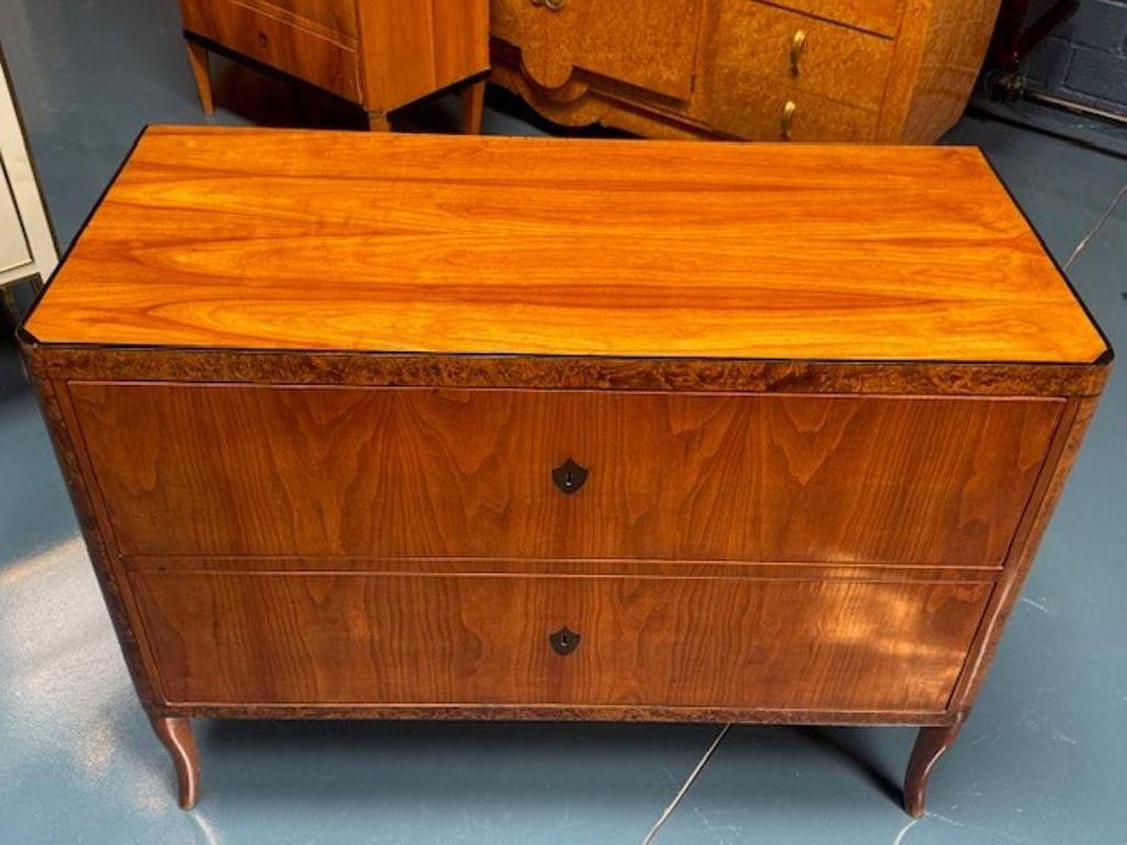 Discover the elegance of the 19th century with this handsome German walnut and elmwood Biedermeier commode. A true antique, this piece exudes the classic sophistication of its era, crafted with the attention to detail and quality that's admired in