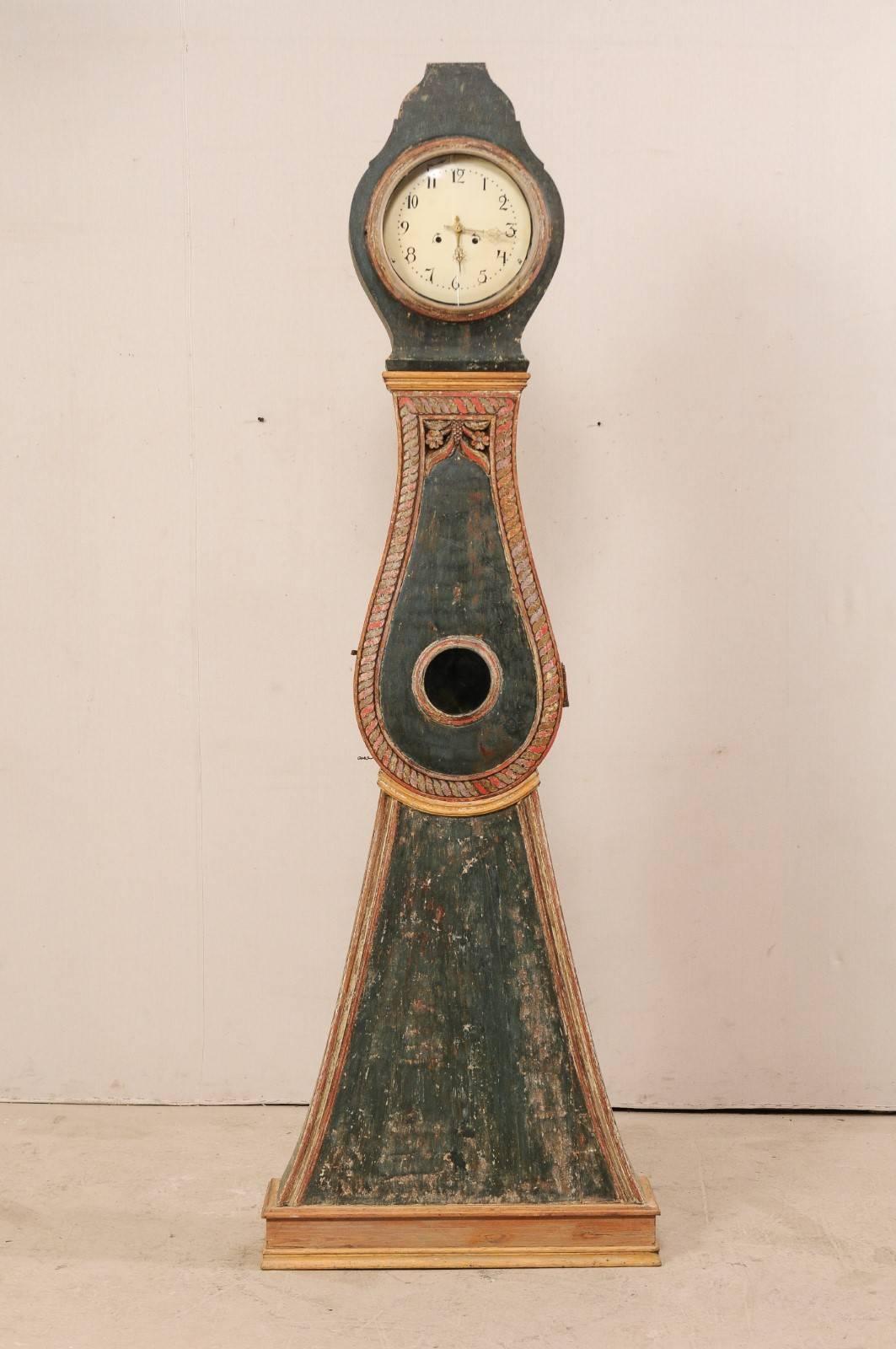 A 19th century painted wood Northern Swedish floor clock. This fabulous 1820s floor clock from Northern Sweden features a raised flat-top crest, it's original round metal face and movements, detailed rope trim details about the centre door case with