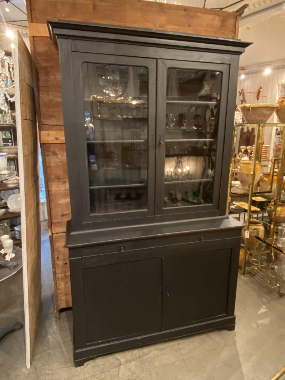 Elegant and beautiful old French 2-part display cabinet, and an ideal decor piece for porcelain and glass storage.

The cabinet consists of an upper display case with double original glass doors, and adjustable shelves. The lower section holds a