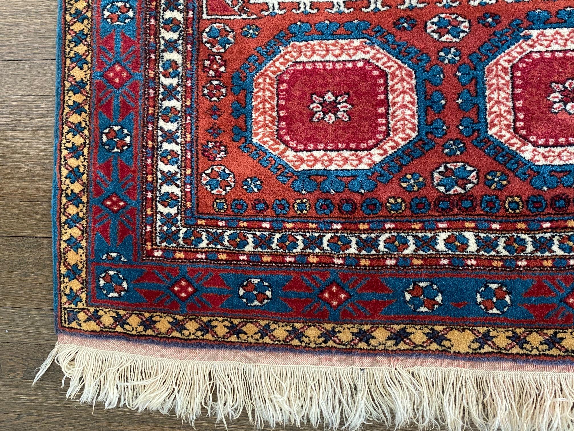 Schöner türkischer Teppich aus Holz in Juwelentönen mit geometrischem Muster in tiefem Rot, Blau und Weiß.

(Patten)