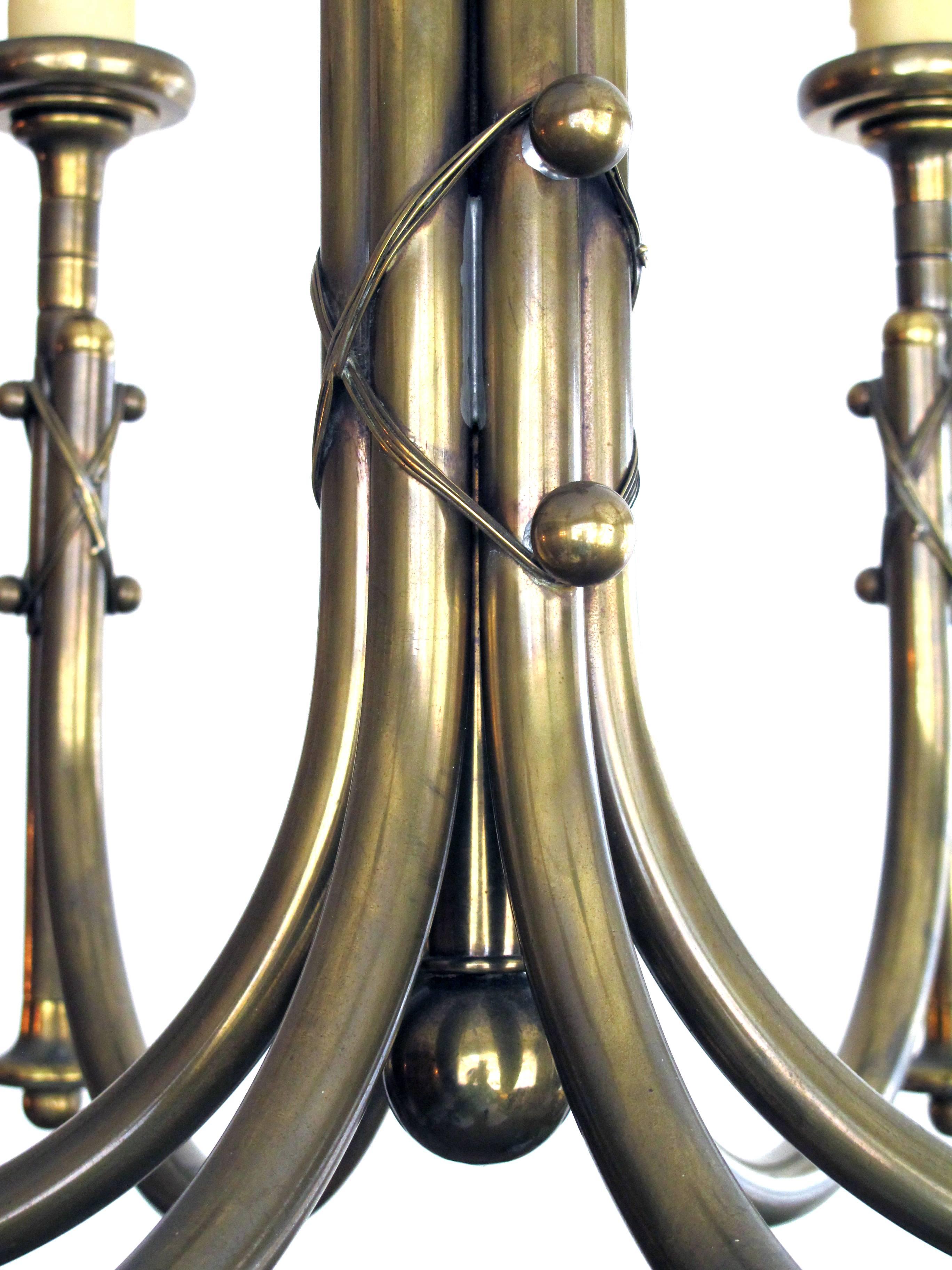 The central cluster column support emanating six scrolled arms supporting upright torches; adorned overall with brass strap-work and spheres