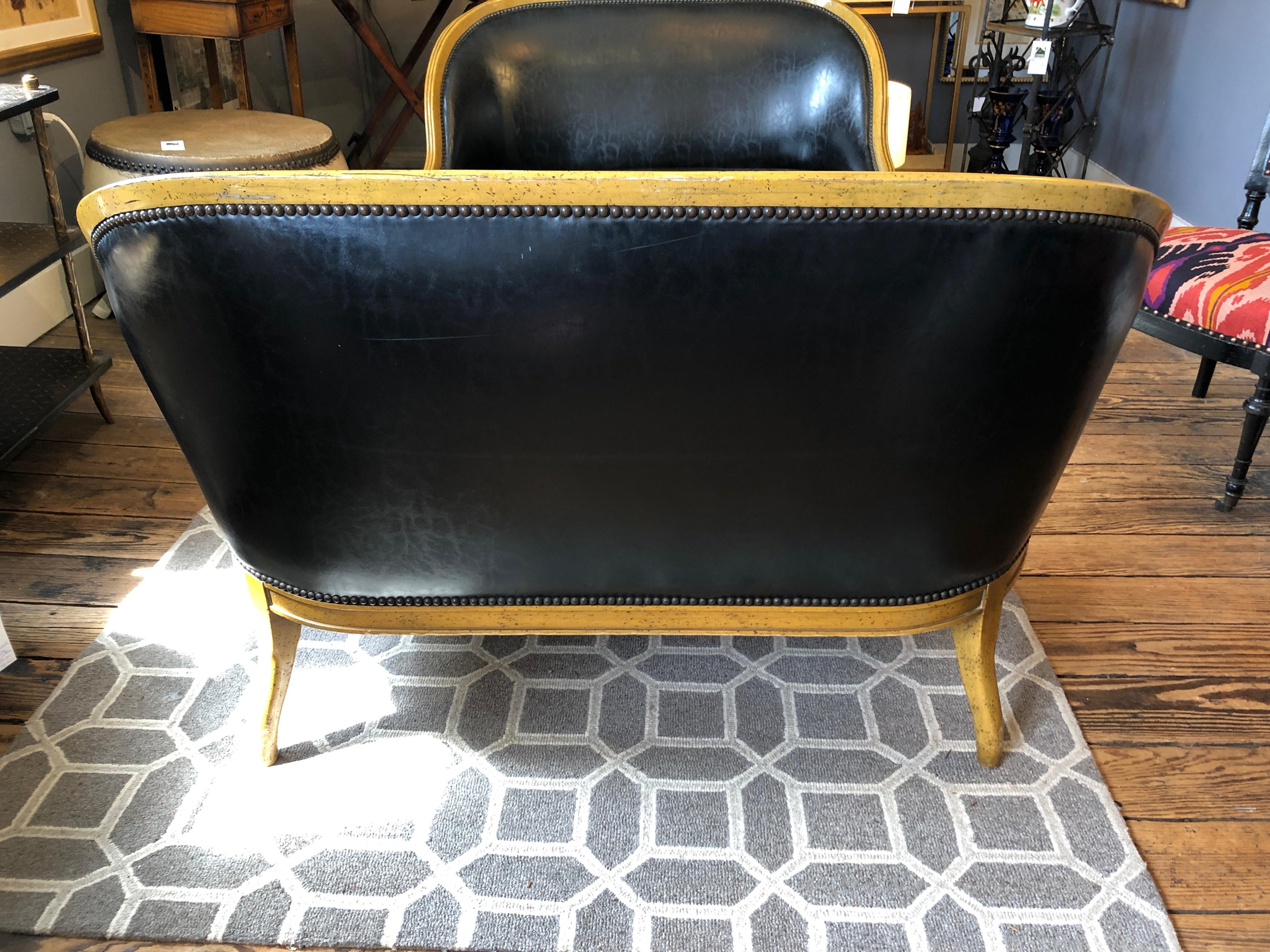 A wonderfully shaped loveseat having handsome fruitwood frame and sexy black faux leather upholstery finished with nailheads. Curvy and beautiful front and back.