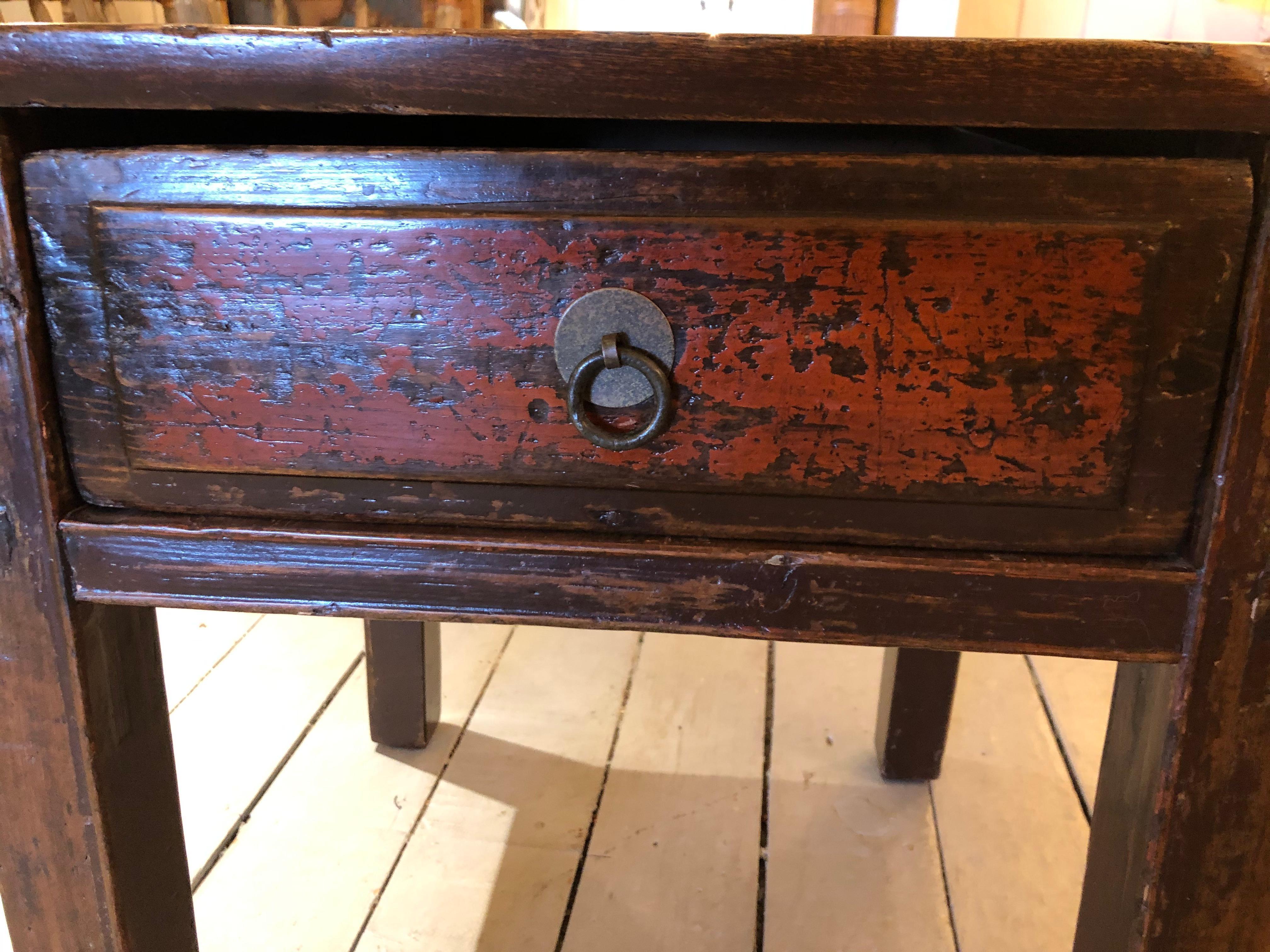 A handsome almost square rustic wooden Chinese end table having irregular shaped edges with wonderful character and a dark orange distressed painted single drawer.