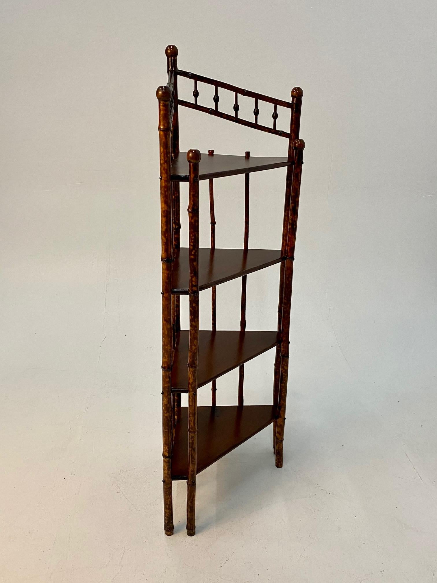 Charming 19th century English corner shelving unit or bookshelf having 4 triangular wooden shelves and beautiful bamboo rod structure.
11