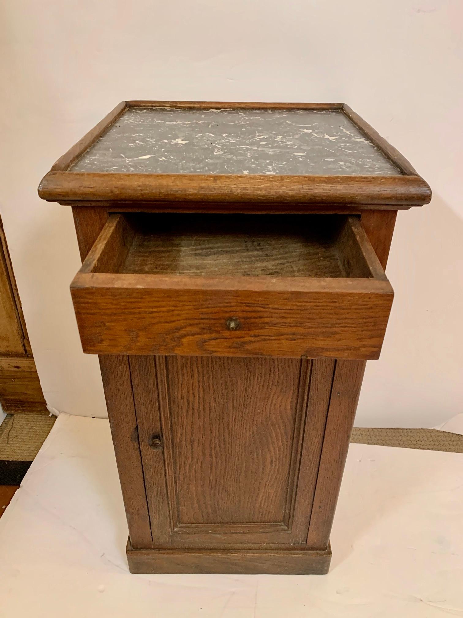 A handsome 19th century oak cabinet stand or side table having lively black and white marble top and one-drawer with storage inside.