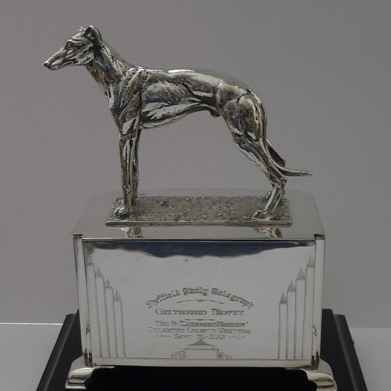A stunning Art Deco trophy / box; topped with a beautifully executed bronze or brass cast Greyhound, finished in silver plate.

The box has some beautiful engraved Art Deco decoration on all sides and the trophy also engraved 