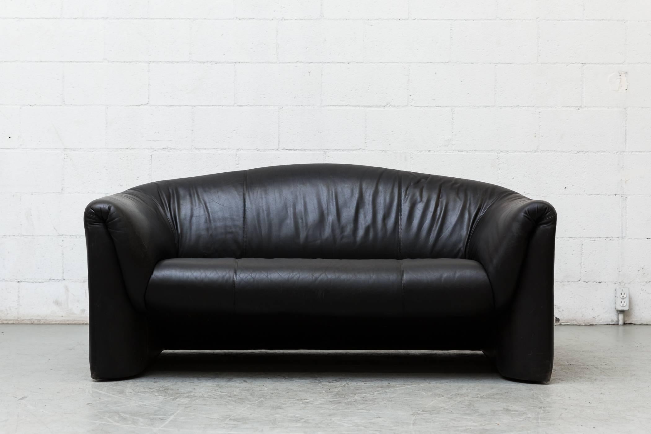 Handsome black leather love seat with top curved back. Vico Magistretti inspired form in good original condition.