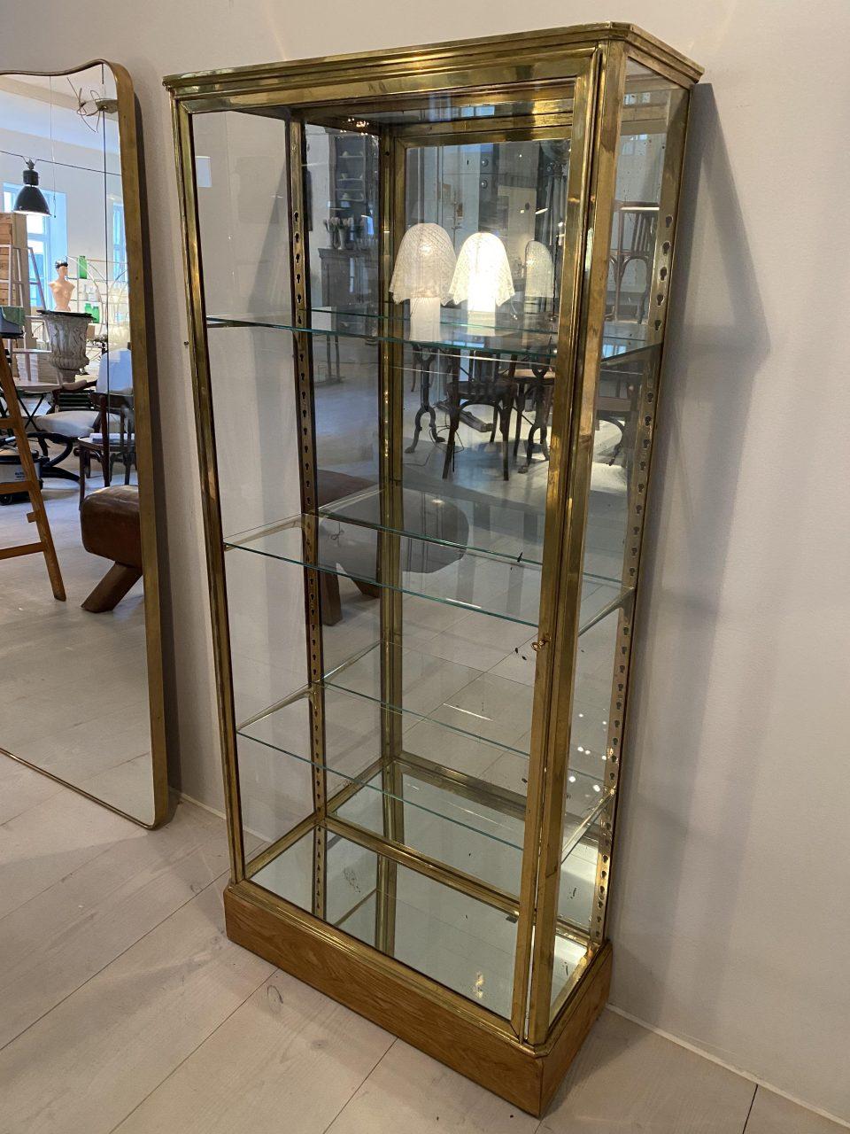 Handsome and well-proportioned display cabinet from France circa 1930s in a stringet Art Deco style. Sleek brass framed profile which comes with its associated key, 3 beautiful faceted glass shelves and adjustable shelf brackets in brass, and a