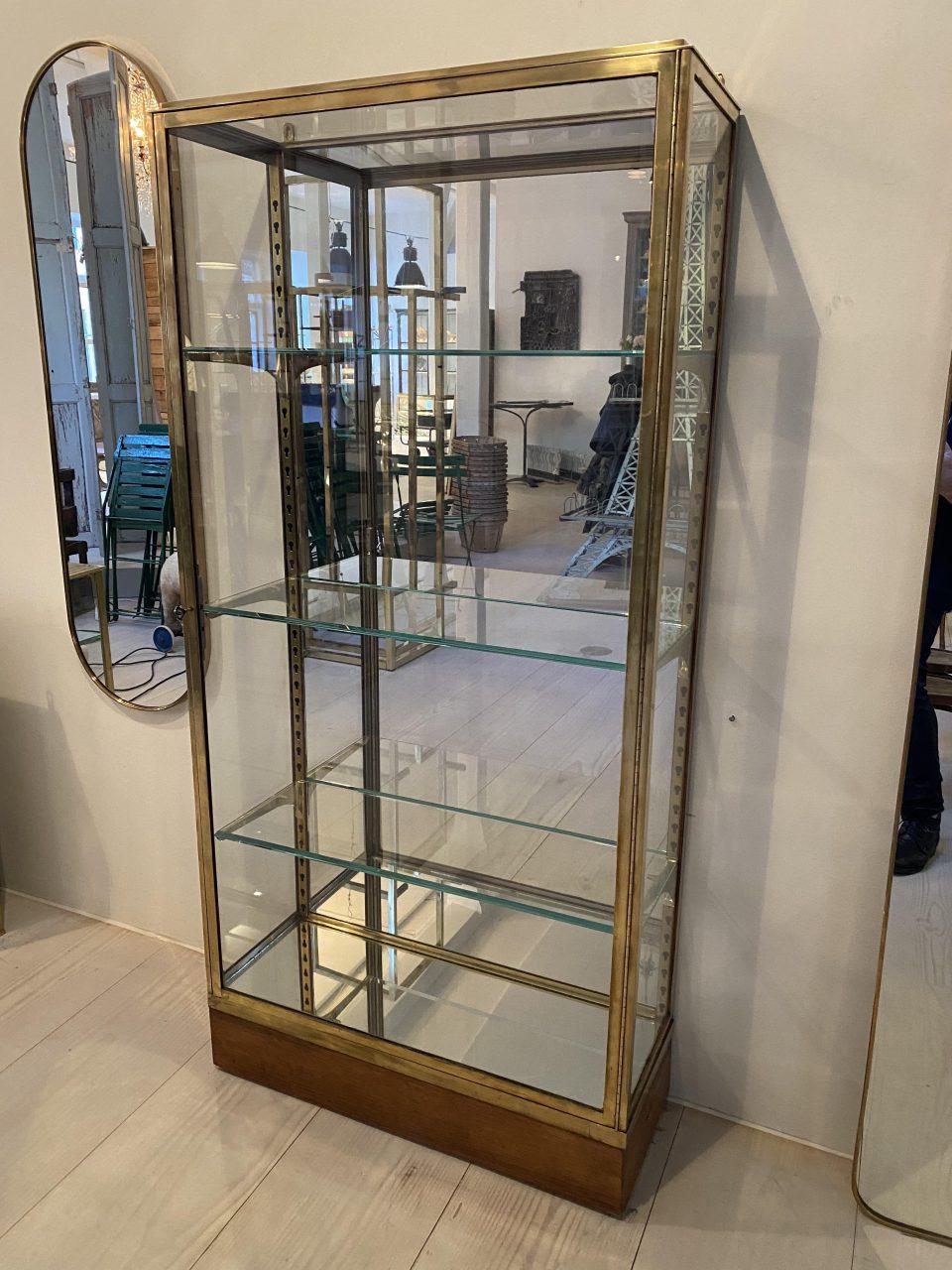Handsome and well-proportioned display cabinet from France circa 1930s in a stringet Art Deco style. Sleek brass framed profile which comes with its associated key, 3 beautiful faceted glass shelves and adjustable shelf brackets in brass, and a