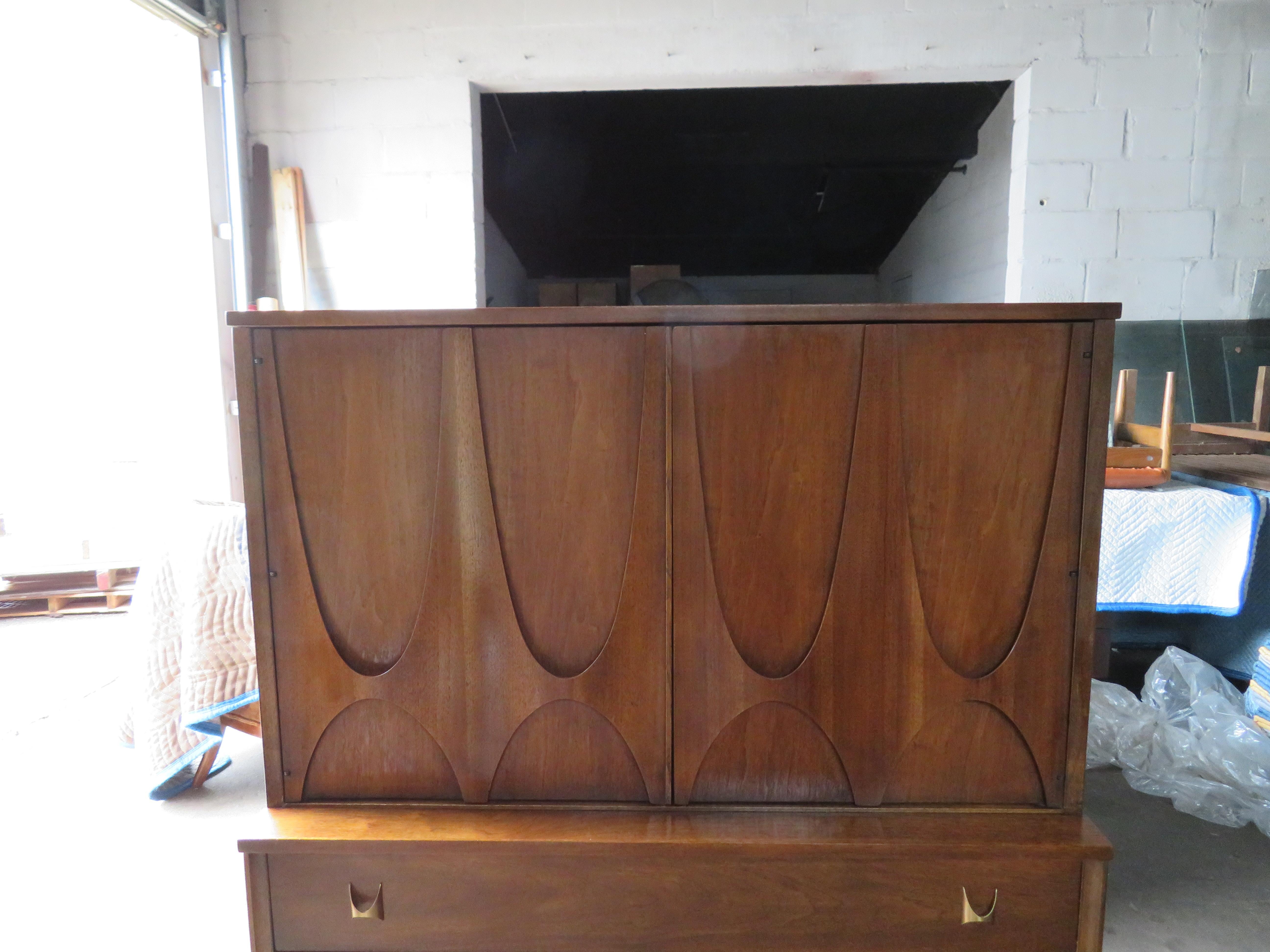 Handsome Broyhill Brasilia tall sculptural walnut chest/dresser. If you think the lines of this chest of drawers are very architectural, you would be right. The Brasilia collection was introduced at the Seattle World’s Fair in 1962 and drew its