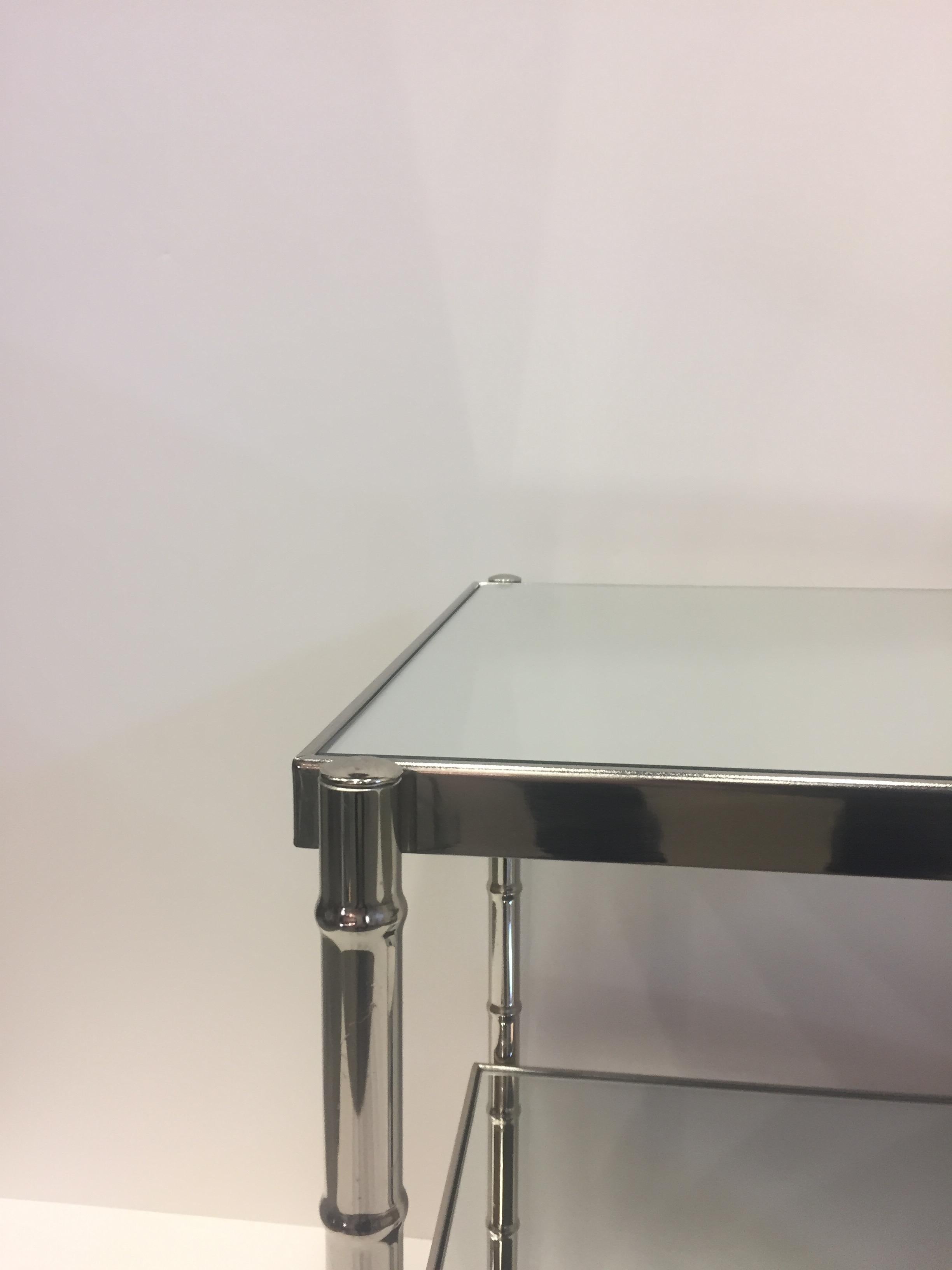 Quality end table having two tiers of mirror and stylish faux bamboo chrome structure.
 