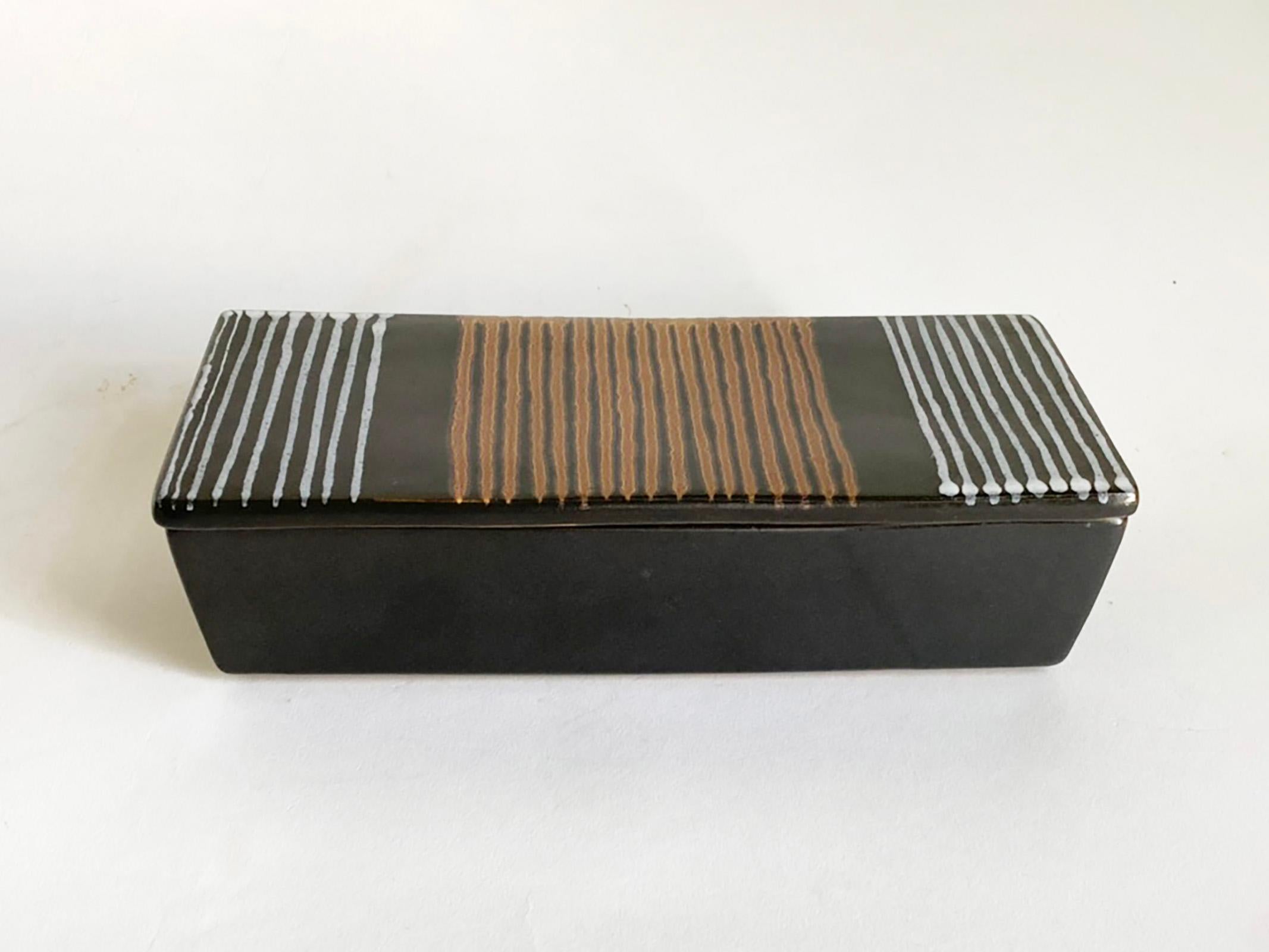 Hier ist eine schöne und seltene überdachte Dose von Glidden Pottery, die höchstwahrscheinlich von Fong Chow entworfen wurde, der für Glidden von  1953 bis 1957. Dieses sehr auffällige Exemplar ist satinschwarz glasiert und hat handgemalte Streifen