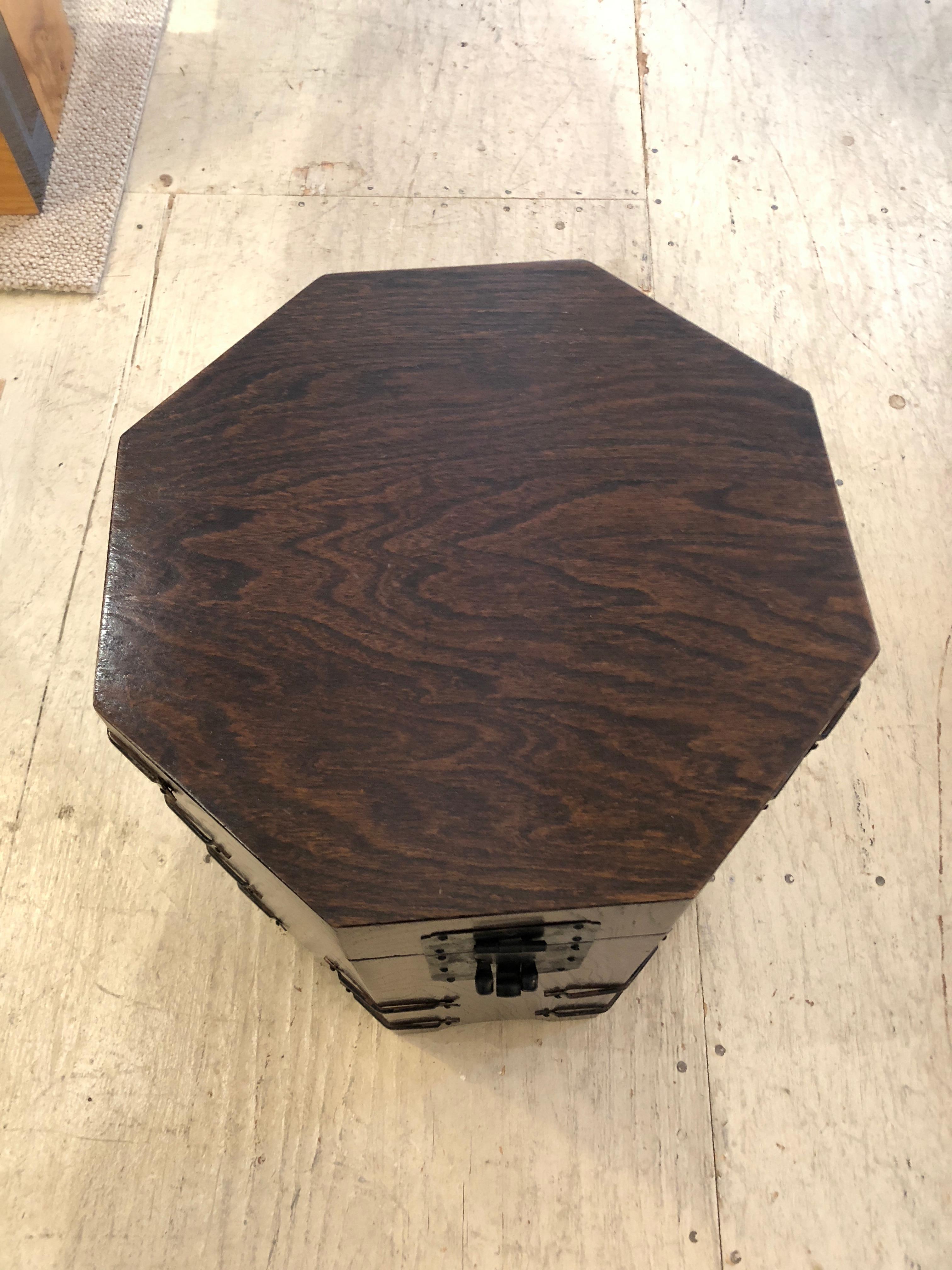 A masculine octagonal oak end table chest that opens to reveal storage inside and is decorated with black iron around the periphery and latch.