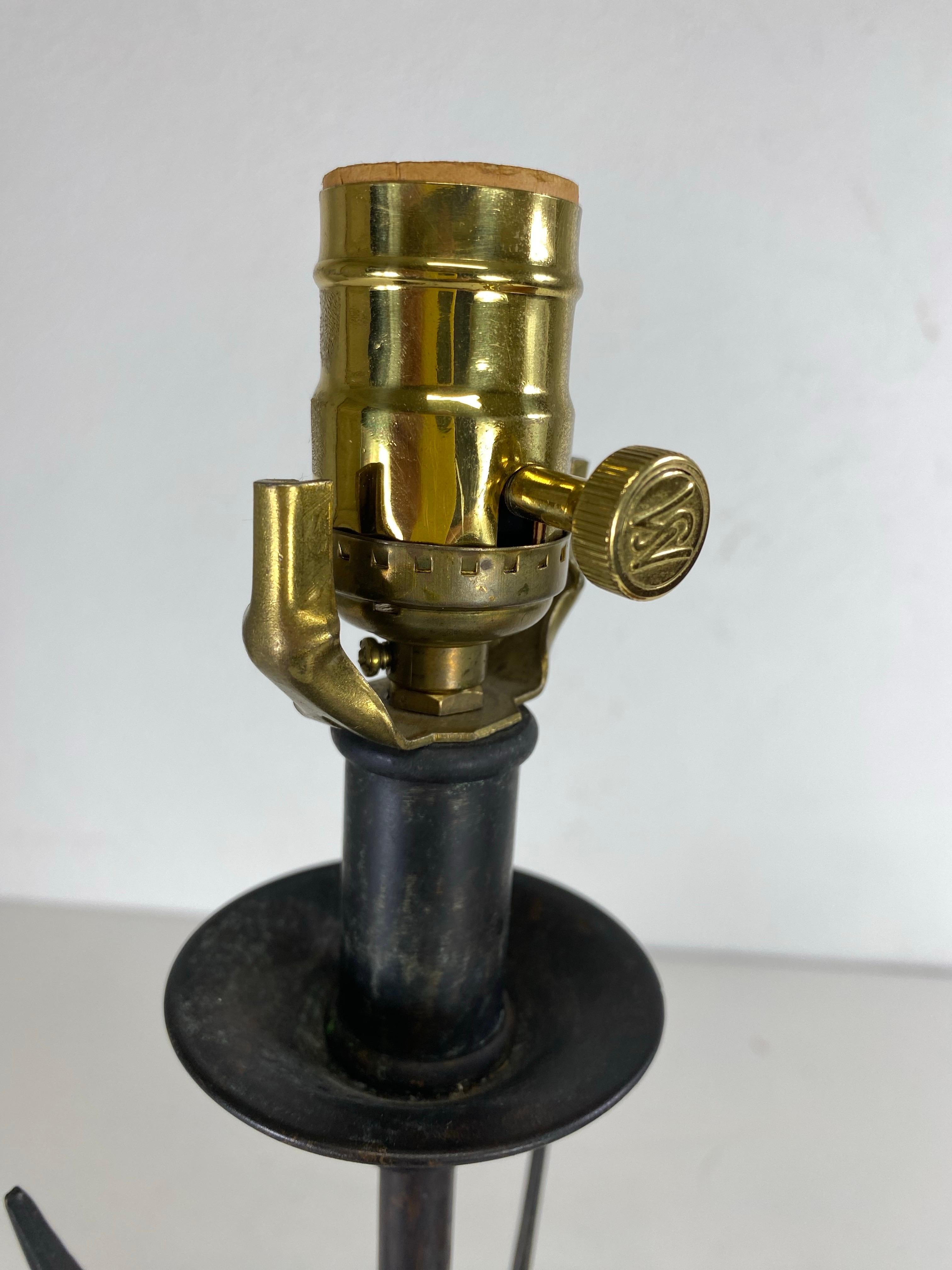This is a vintage empire inspired leather and iron table lamp by Maitland Smith. This table lamp has the classic three arrows forged together in the center with a rope design. The tripod base is tooled tobacco colored leather. The lampshade is