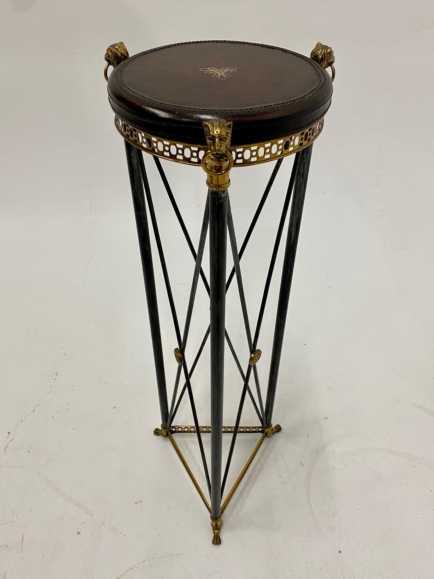 A great looking Empire style pedestal having ebonized steel criss cross base with brass medallions and lions as well as a handsome tooled leather circular top.