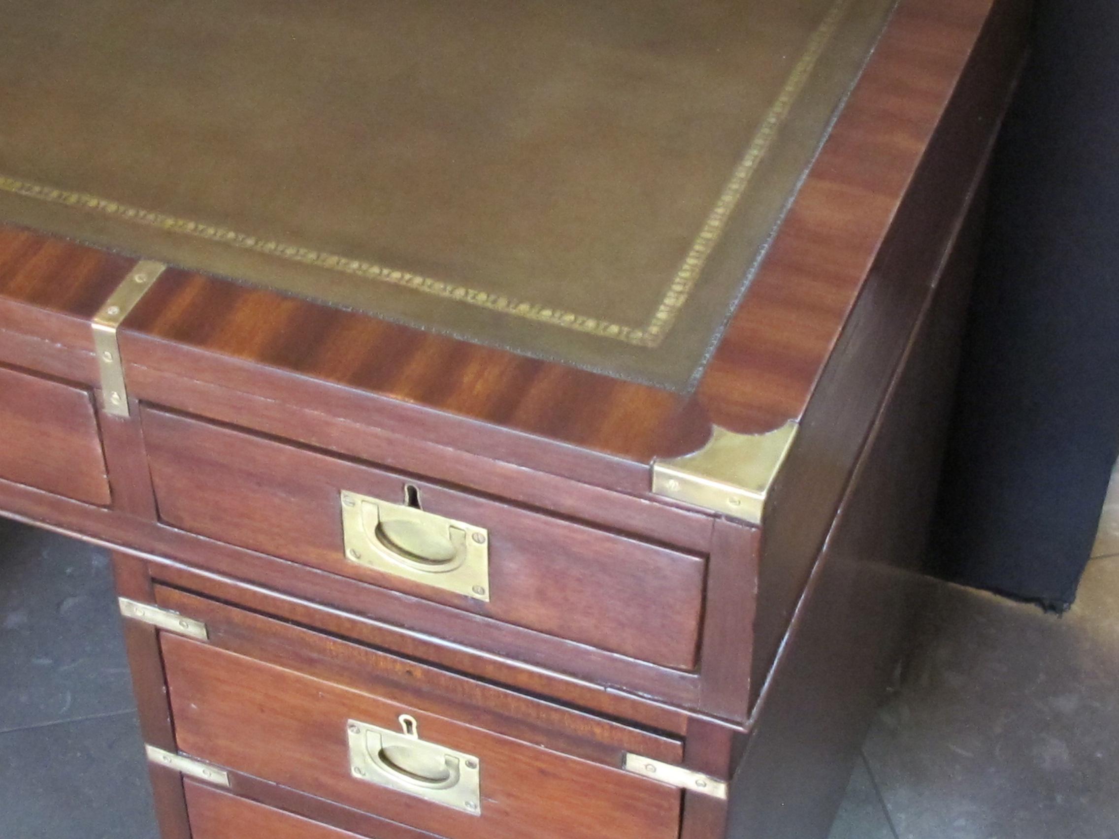 In three pieces, with hand-tooled inset leather top above an apron fitted with 3 drawers; all resting on dual 3-drawer pedestals raised on bracket feet.