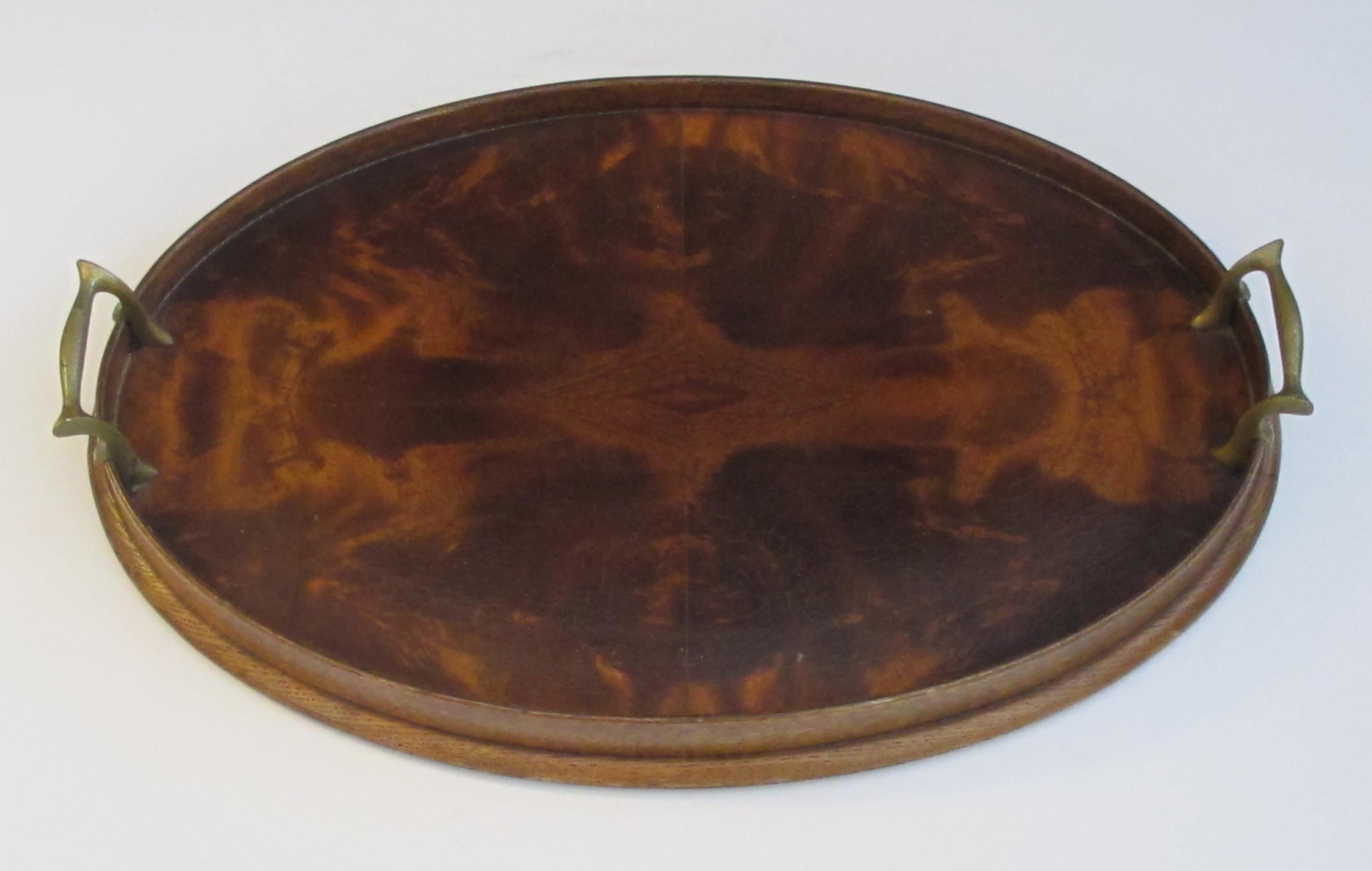 The well-figured oval tray of mirror-veneered mahogany all flanked by solid brass handles.