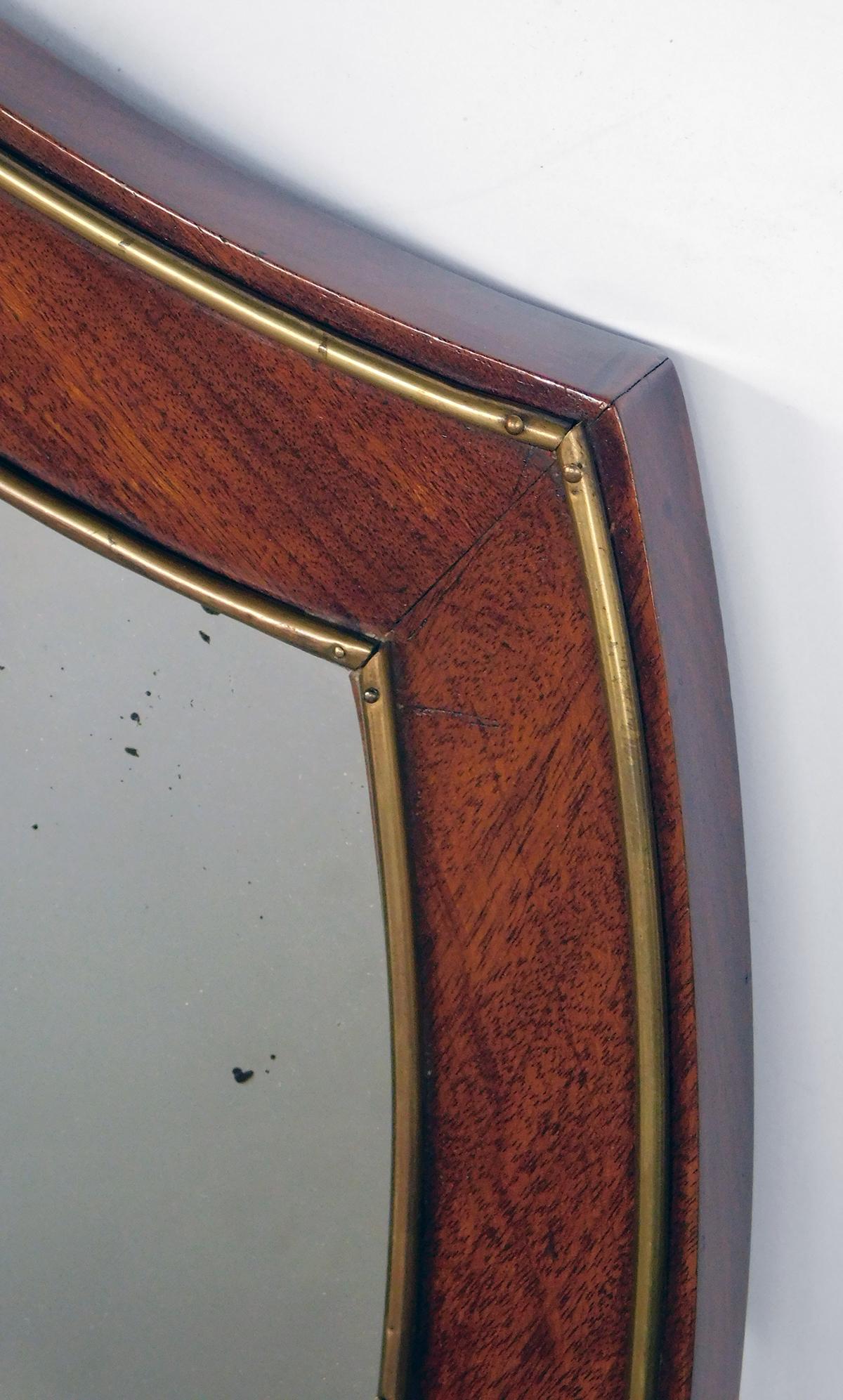De forme bouclier dans le goût néoclassique, le cadre en acajou avec décoration en laiton appliqué.