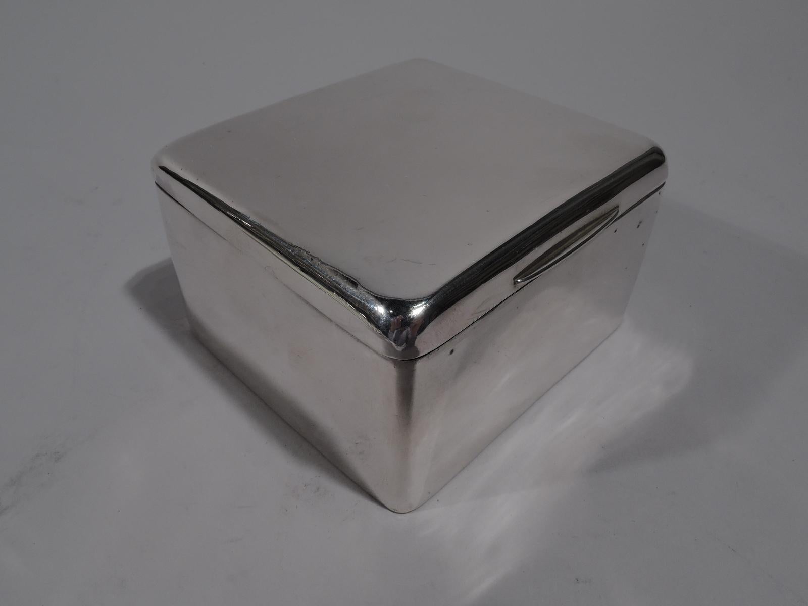 Edwardian sterling silver box. Made by Arthur & John Zimmerman in Birmingham in 1904. Square with hinged and tabbed cover. Box interior cedar lined. Cover interior gilt. Box underside leather lined. A handsome receptacle for rings and cufflinks.