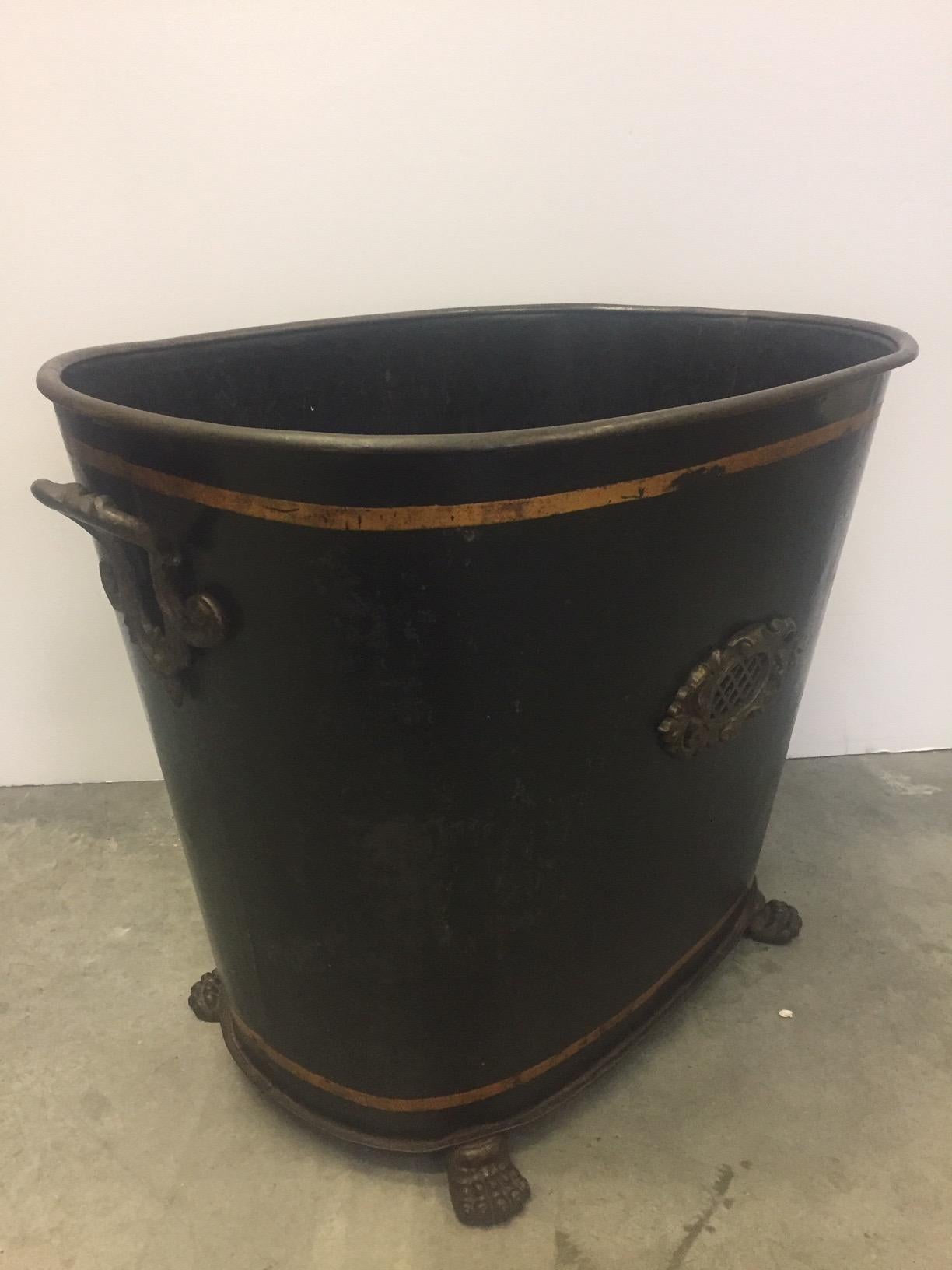 A handsome black tole firewood bucket from England having handsome brass mounts, handles and paw feet, tapering down to 17