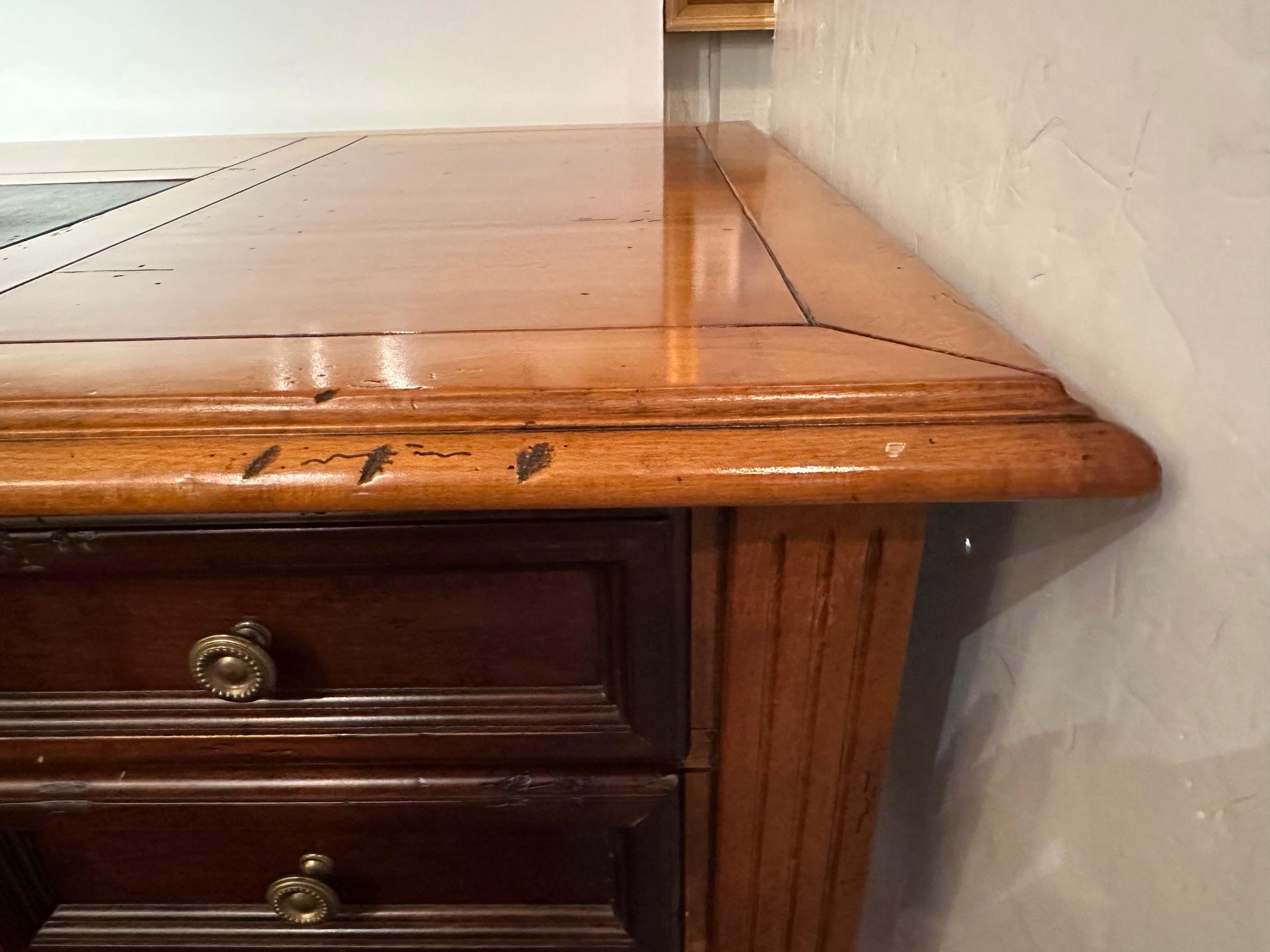 English style beautiful fruitwood writing desk having black leather blotter on top.  Distressed marks intentional to add character to the piece.  Tapered reeded legs terminating in brass casters.

59” W x 31.5” D x 30.5” H
Opening 24” H x 24” W