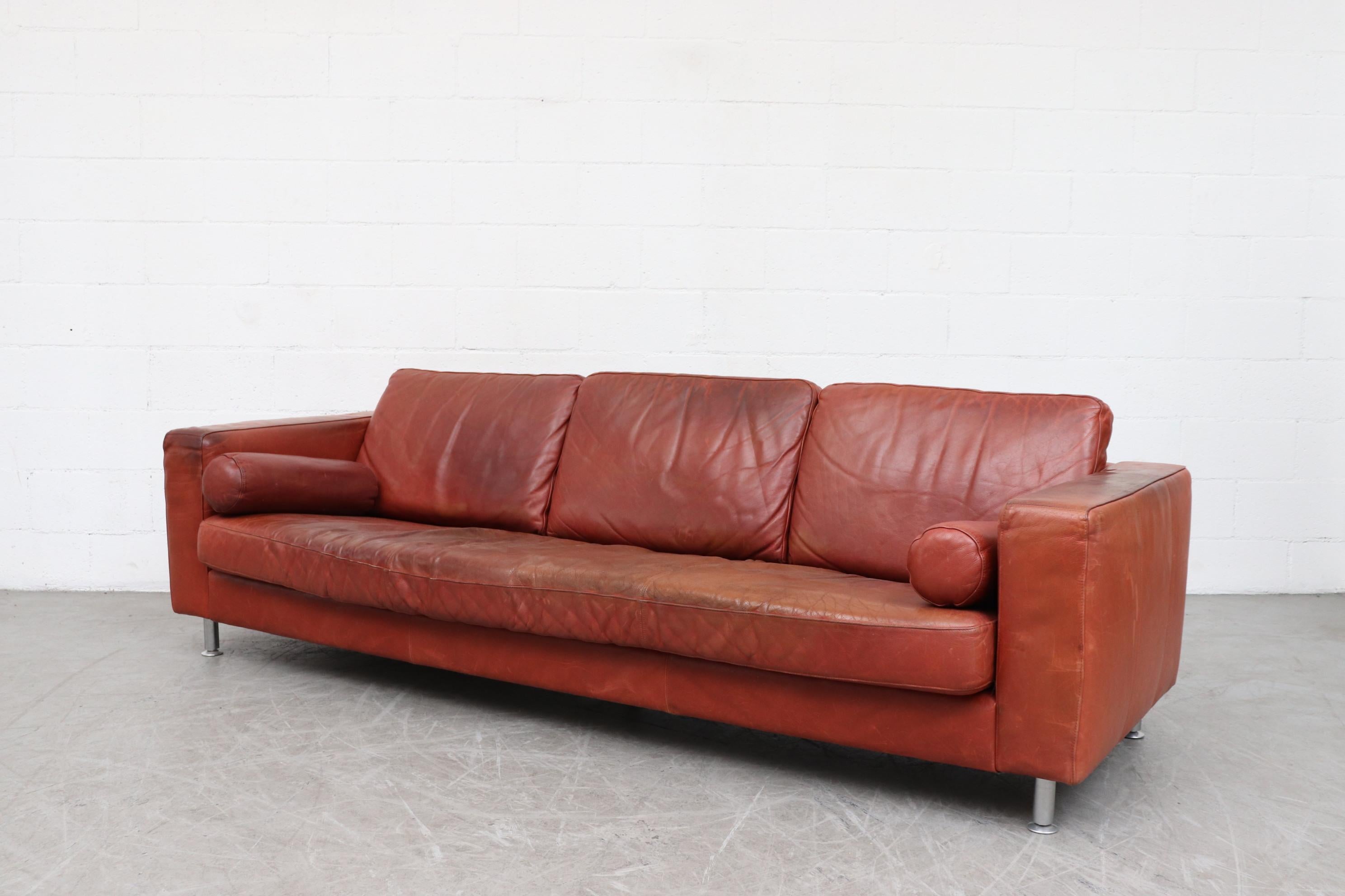 Handsome extra long Knoll style streamline cognac colored leather sofa with 2 bolster pillows and brushed chrome legs, circa 1990. Nice natural patina with visible signs of wear. In very original condition.