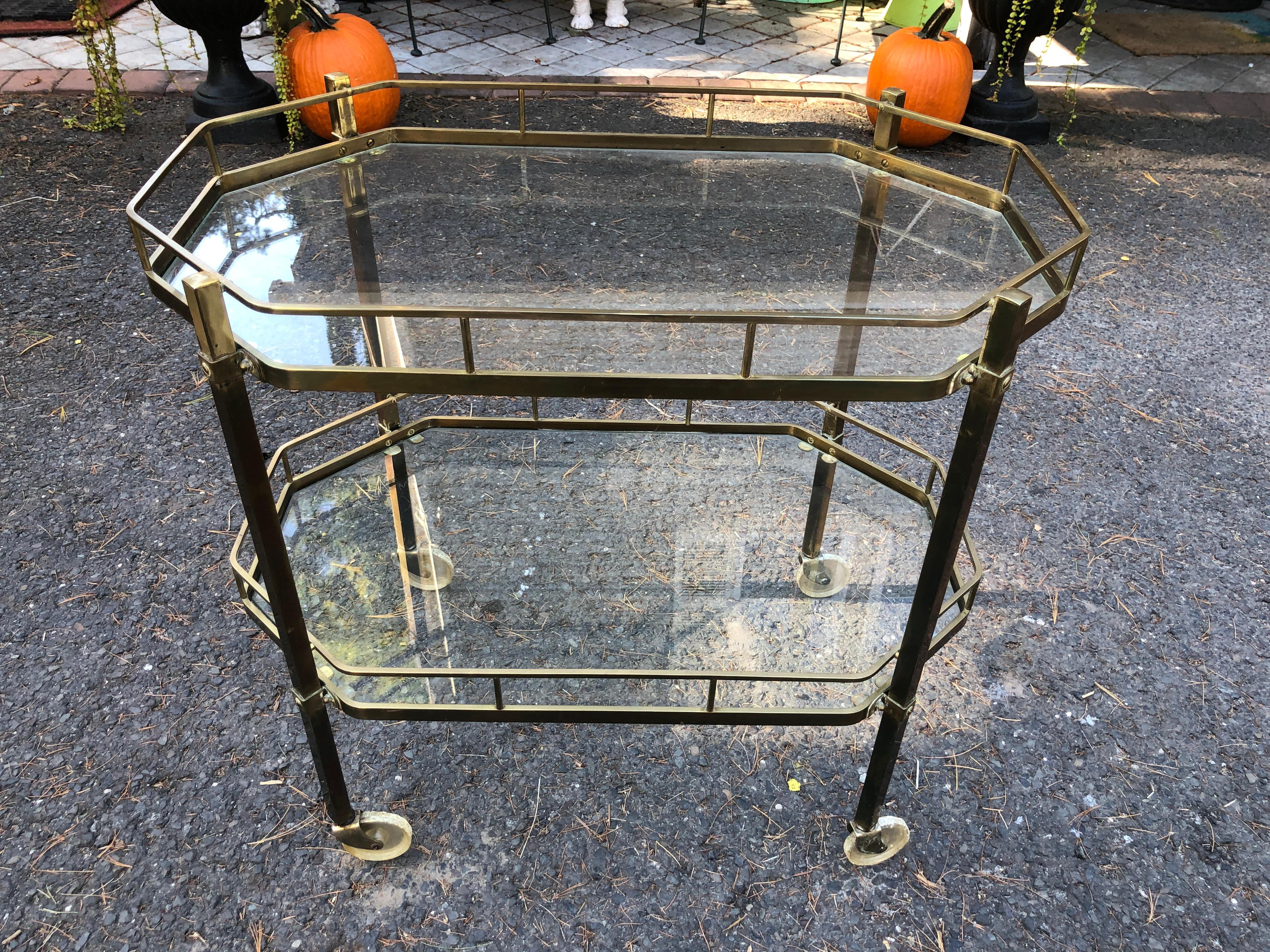 Handsome French octagonal shaped two tiered bar cart in brass with acrylic wheels. This piece measures 28.5