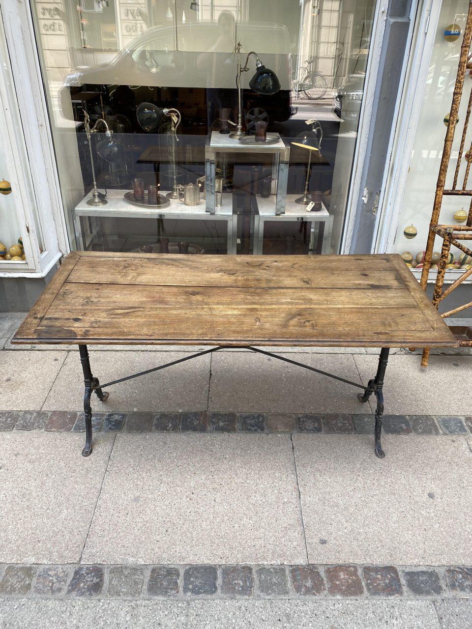 Large and handsome bistro table, with a cast iron under frame and elegant wooden tabletop, which has a wonderful warm and welcoming sheen. Used as a dining table in a Classic French bistro. Would be a lovely alternative too as a console table in a