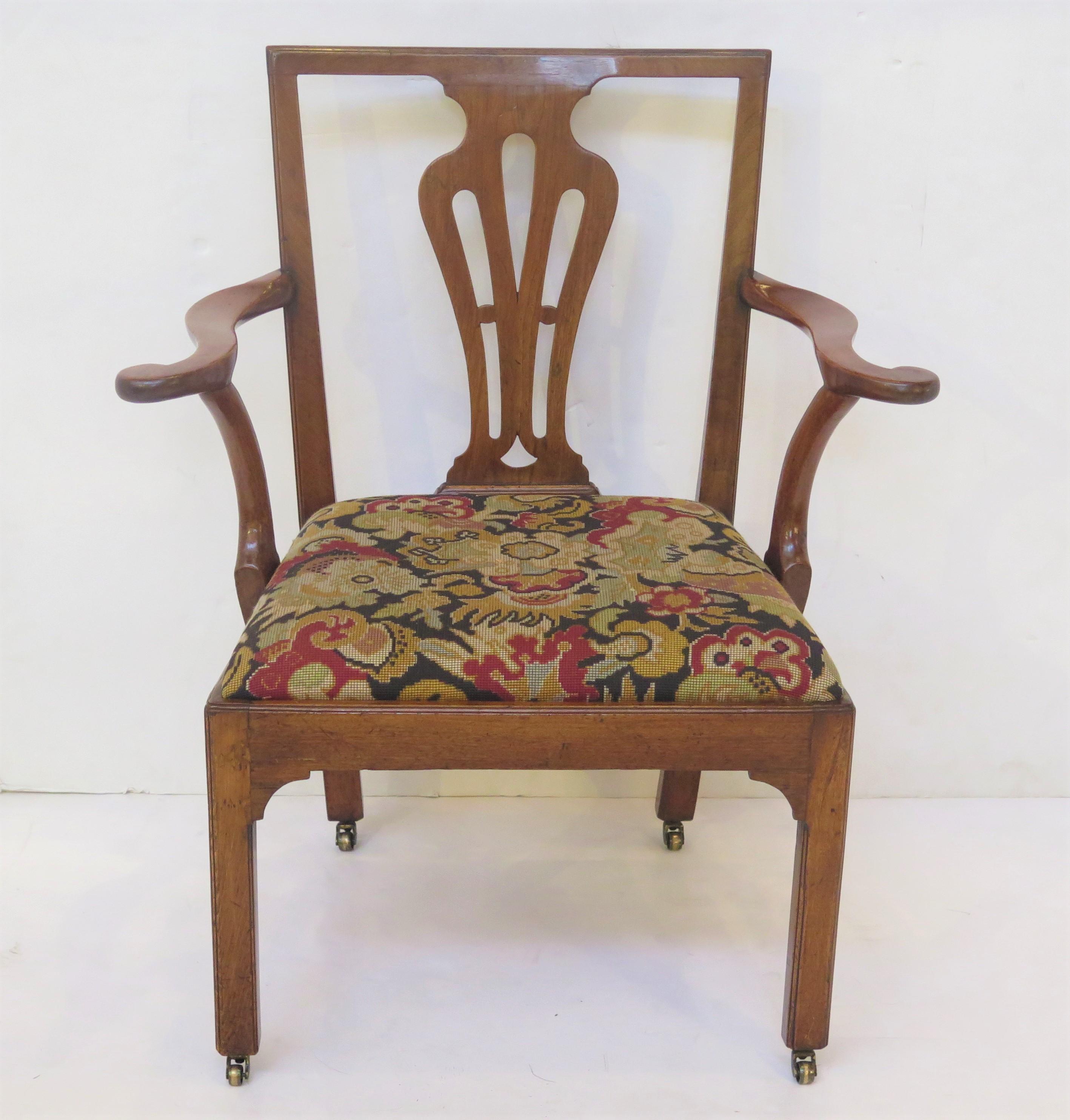 a handsome Georgian armchair or desk chair, walnut with needlepoint slip seat, flat-top crest rail above a pierced vasiform splat, scrolled arms, upholstered seat raised on Marlborough legs and with small brass castors, England. 18th century