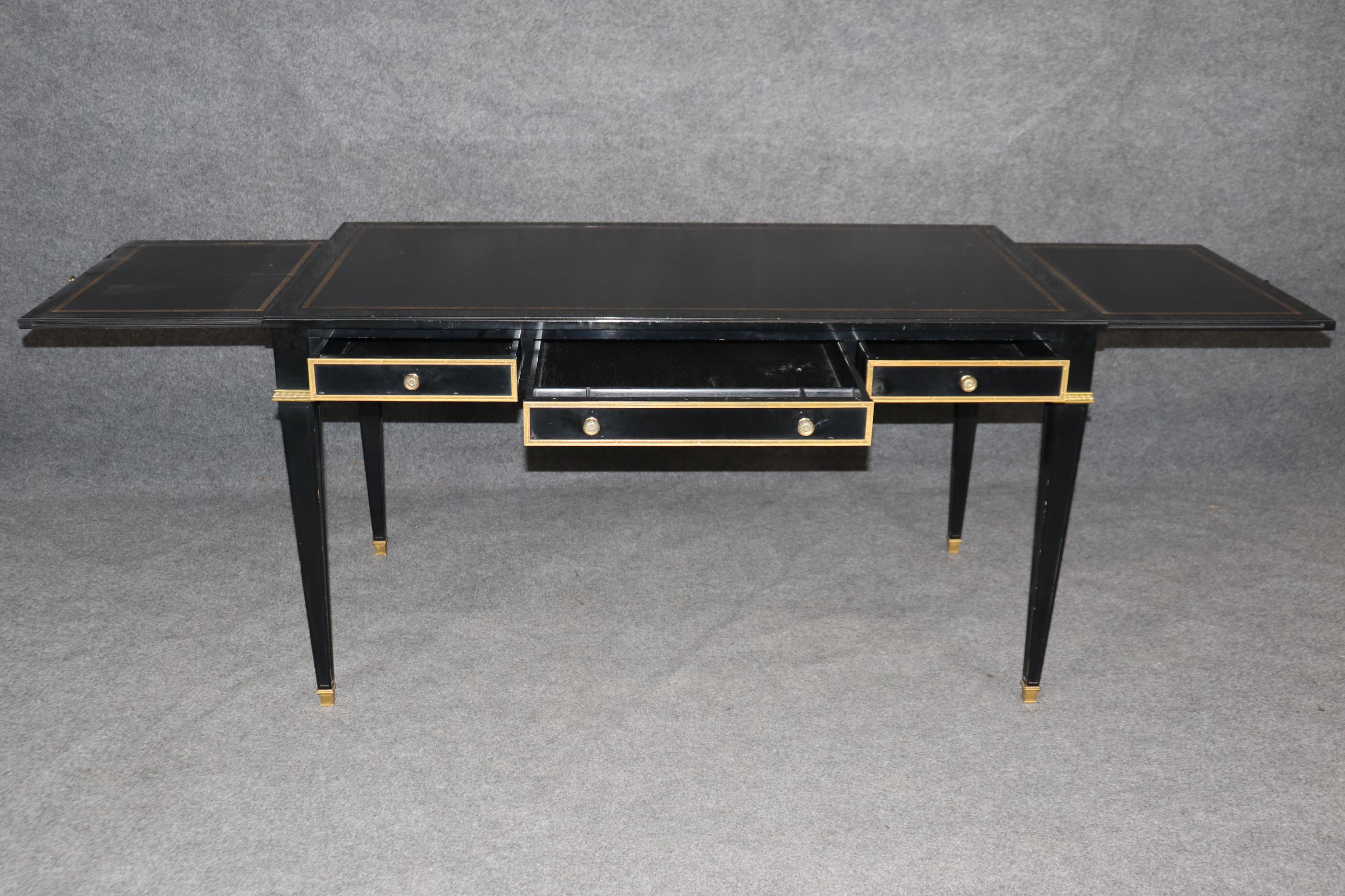 Questa è la quintessenza della scrivania direzionale Maison Jansen in classico ebano originale e bronzo dorato fuso e ferramenta. Il piano in pelle è in ottime condizioni con rilievi in oro e la scrivania presenta due guide estraibili anch'esse con