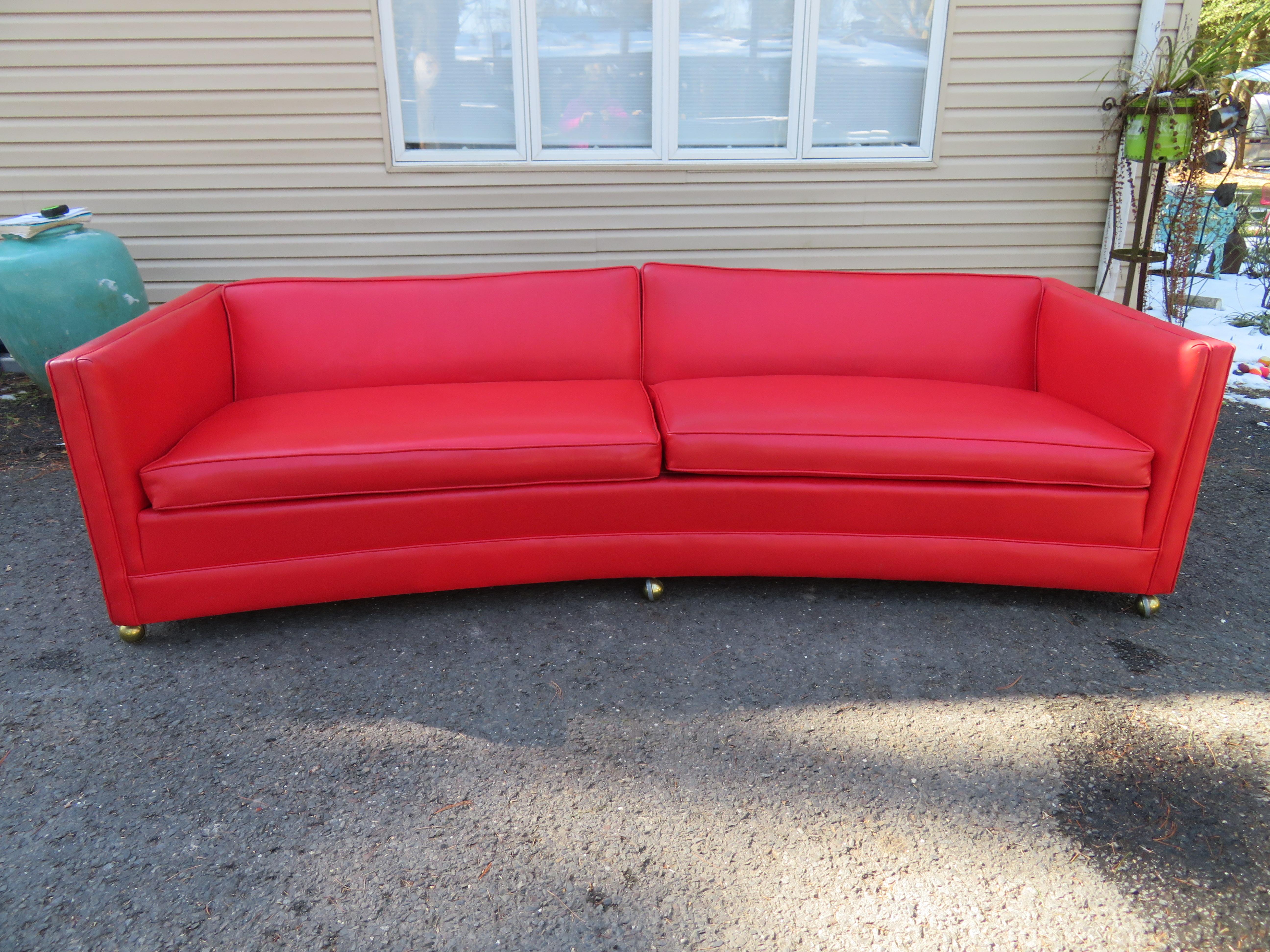 Handsome Harvey Probber attributed curved even arm sofa. This sofa retains its original red faux leather in nice vintage condition. It shows light wear but it is very presentable as is. This sofa is not only stylish but is very comfortable. It