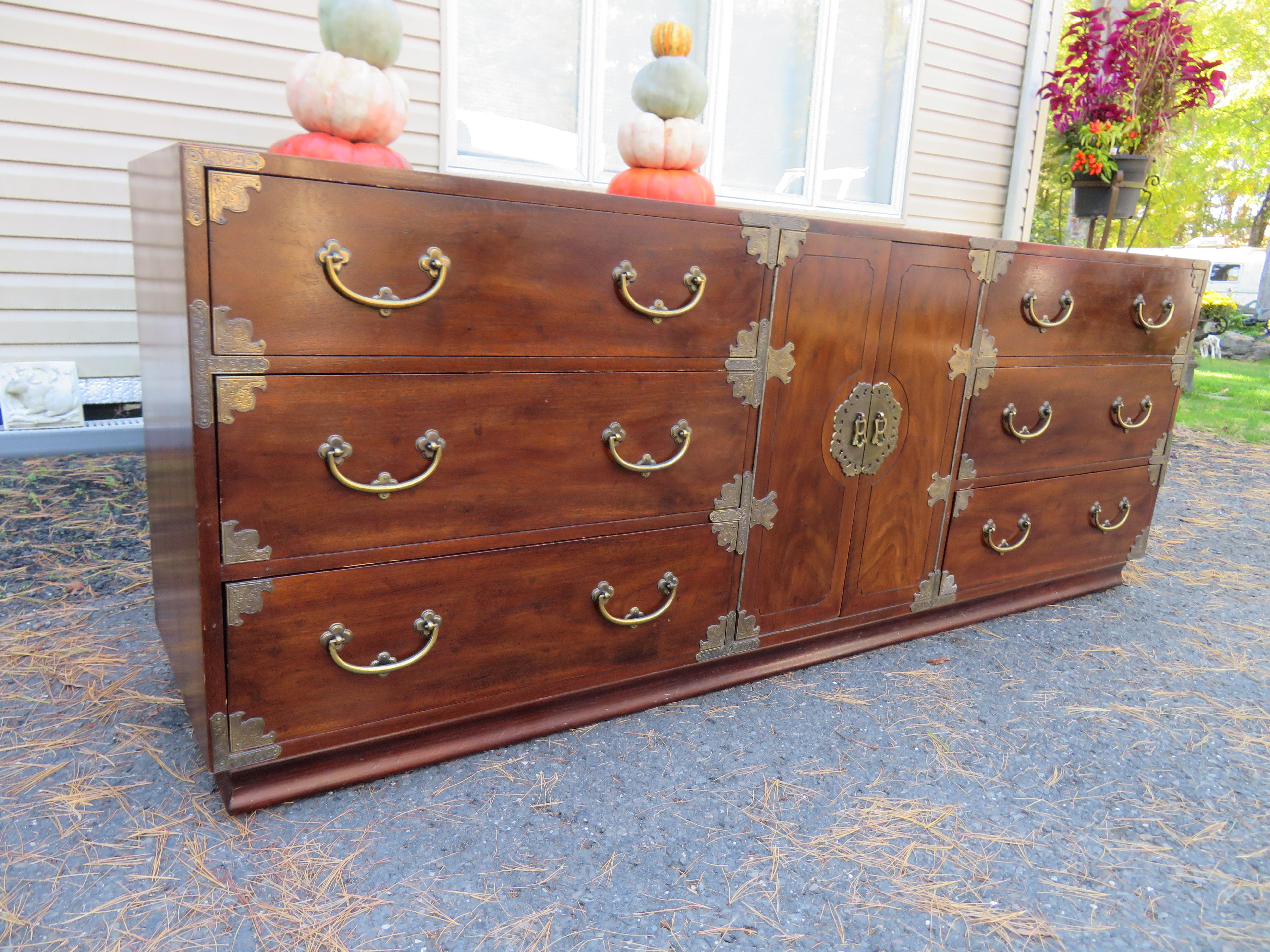 Gorgeous Midcentury campaign Tansu style credenza or long dresser by Henredon Fine Furniture. This credenza features a clean, sleek Midcentury design with an Asian flair. It offers ample room for storage with 9 deep drawers. We love the stylish