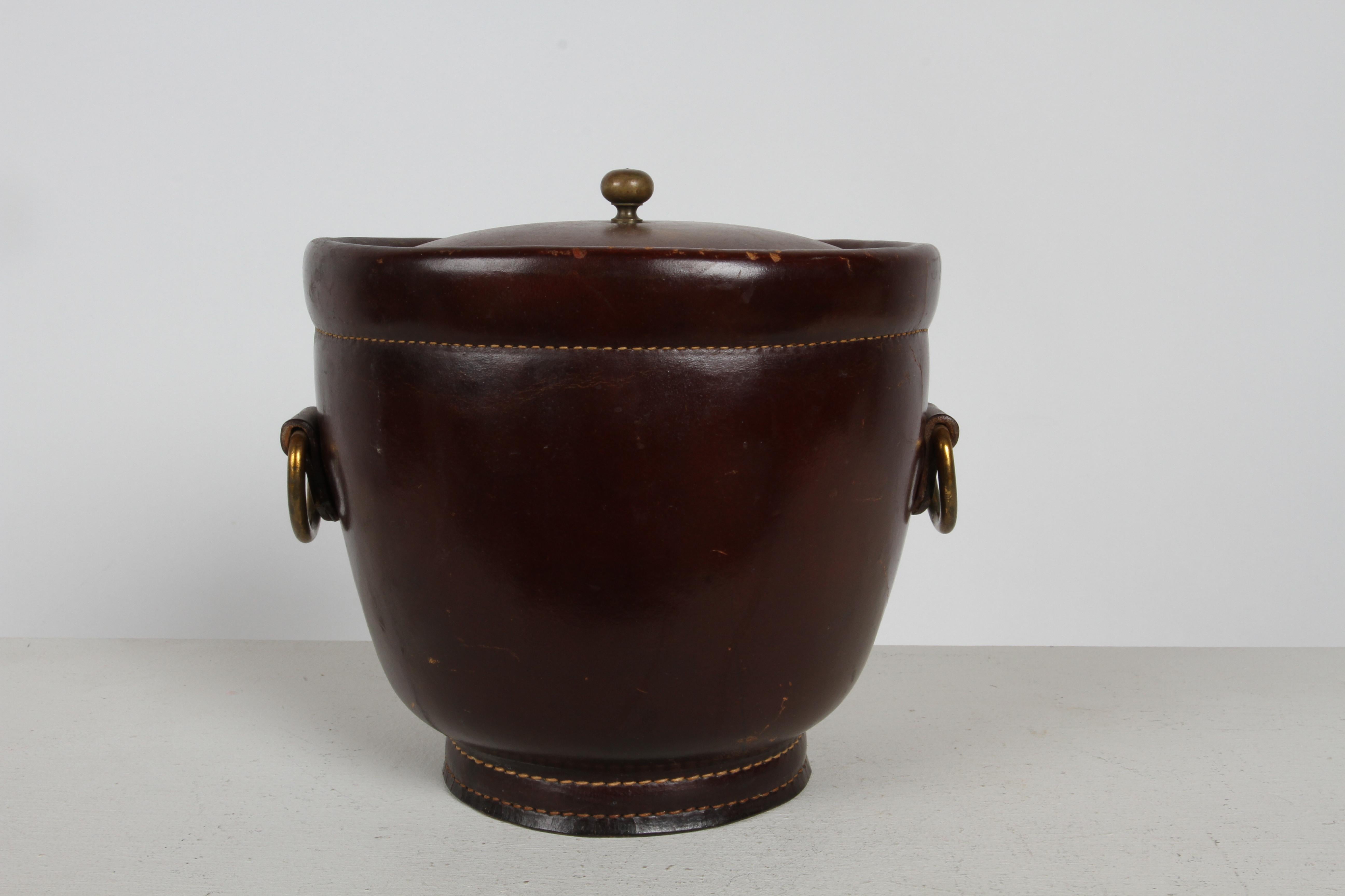 Handsome 1960s Jacques Adnet style vintage leather & brass ice bucket with heavy stitching , brass loop side handles , brass lid knob with gold anodized aluminum liner insulated by fiberglass. Scuffs to leather, wear and dings to liner. Unmarked