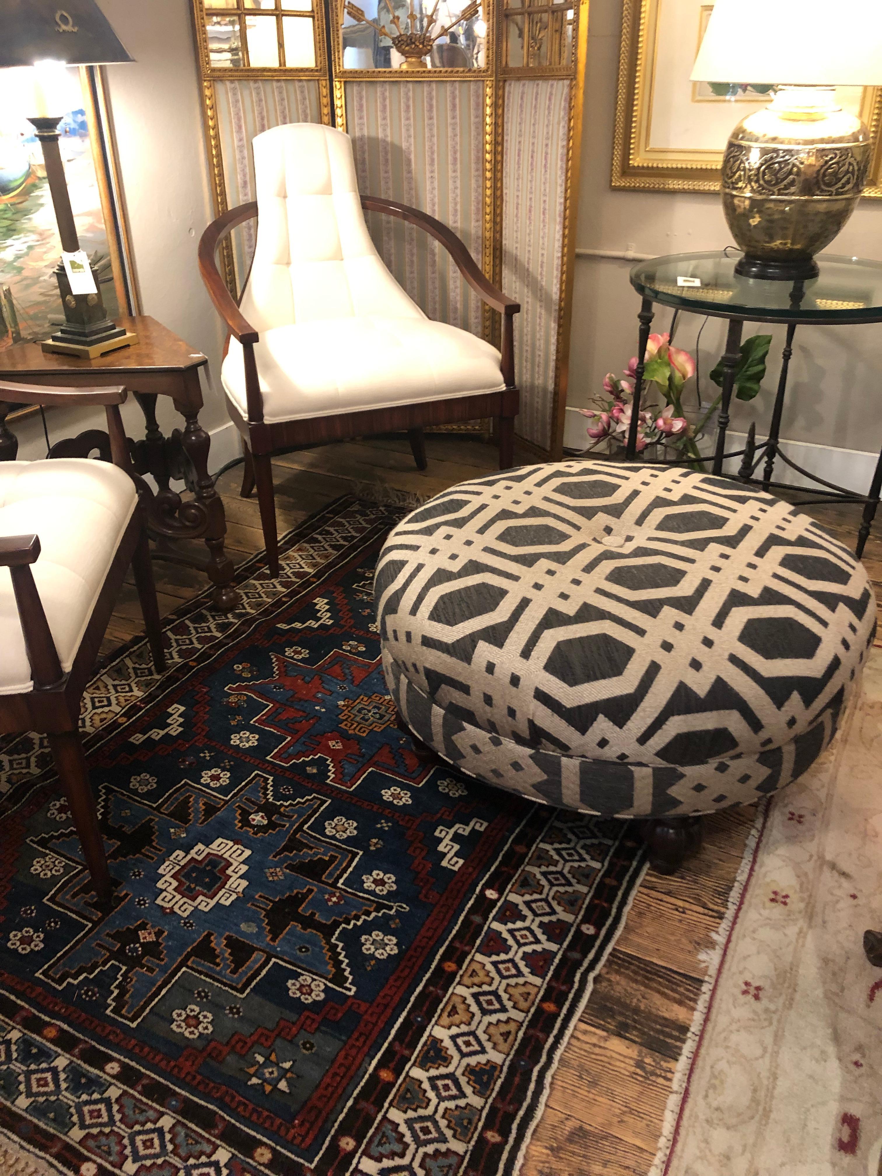 A striking versatile round ottoman upholstered in handsome blue and sandy beige textured lattice pattern fabric and resting on mahogany bun feet.