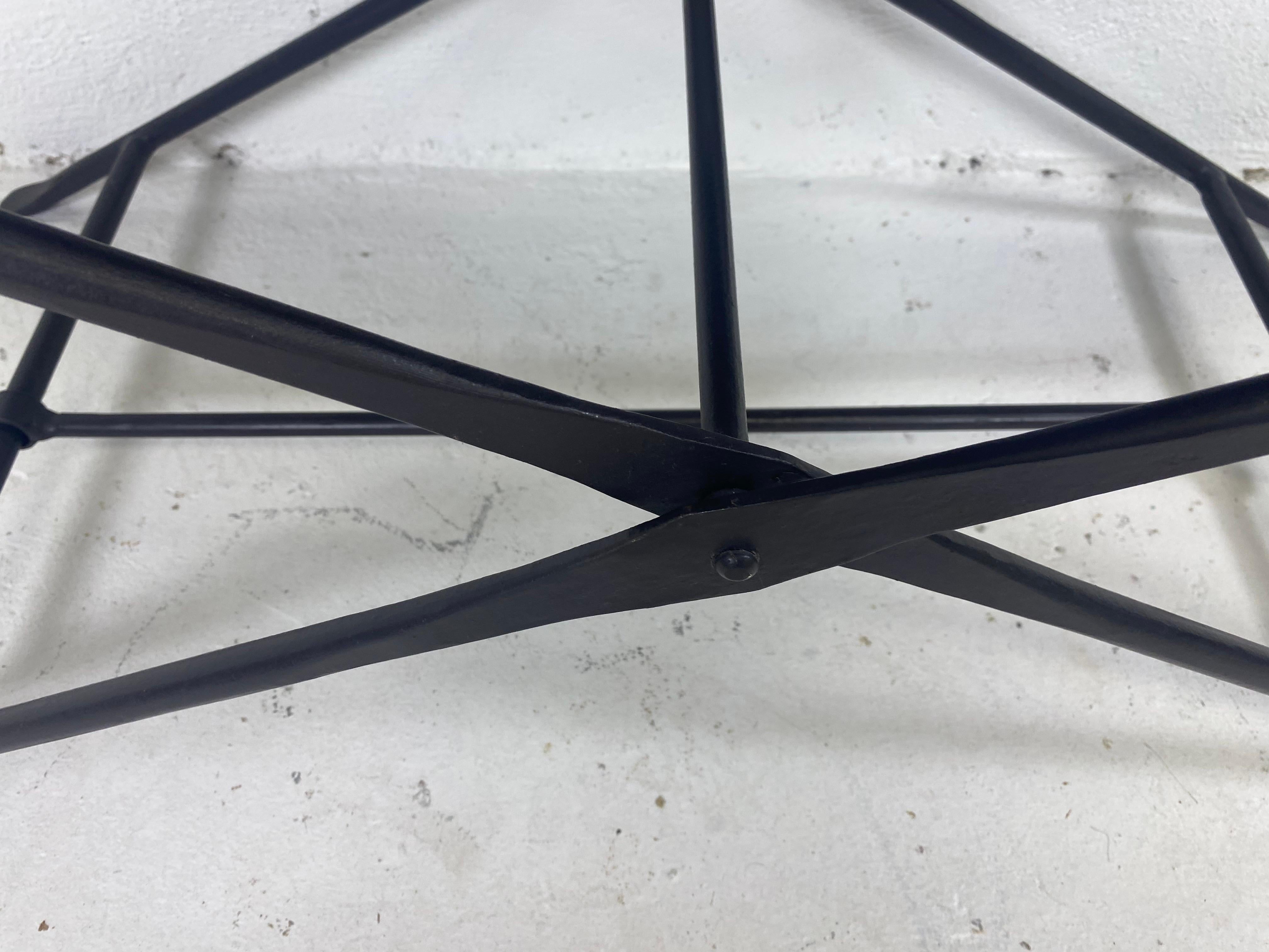 This is a hand wrought iron and leather campaign style bench. This bench has a dark brown leather basket weave to the seating. The bench has a hand wrought iron sleek empire style frame that folds down.