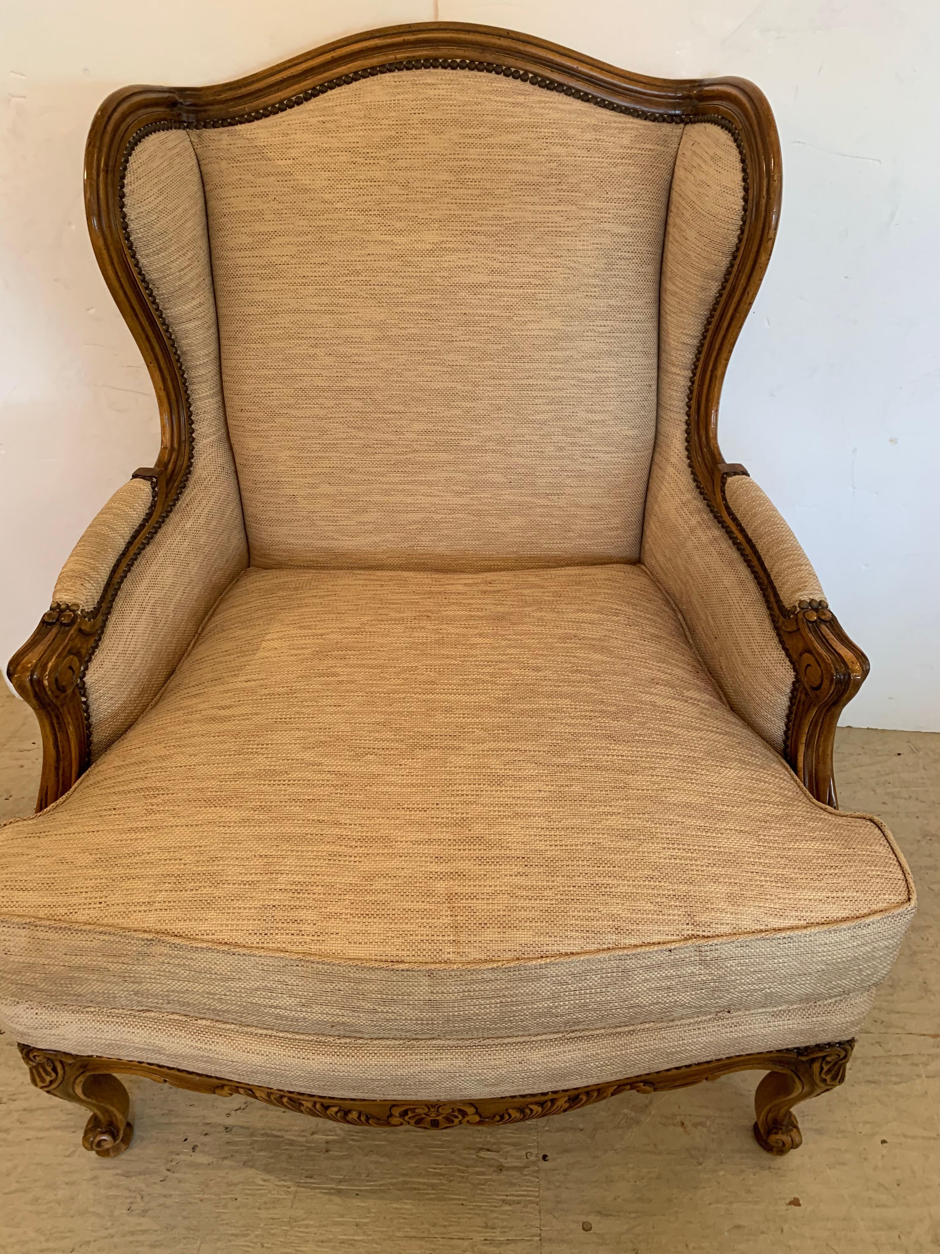 A beautifully made TRS bergere chair inspired by the classic Louis XV bergere form, this quality reproduction armchair has a solid hand carved exposed wooden frame with antique walnut finish and shell motifs and fine cabriole legs. Upholstered in a