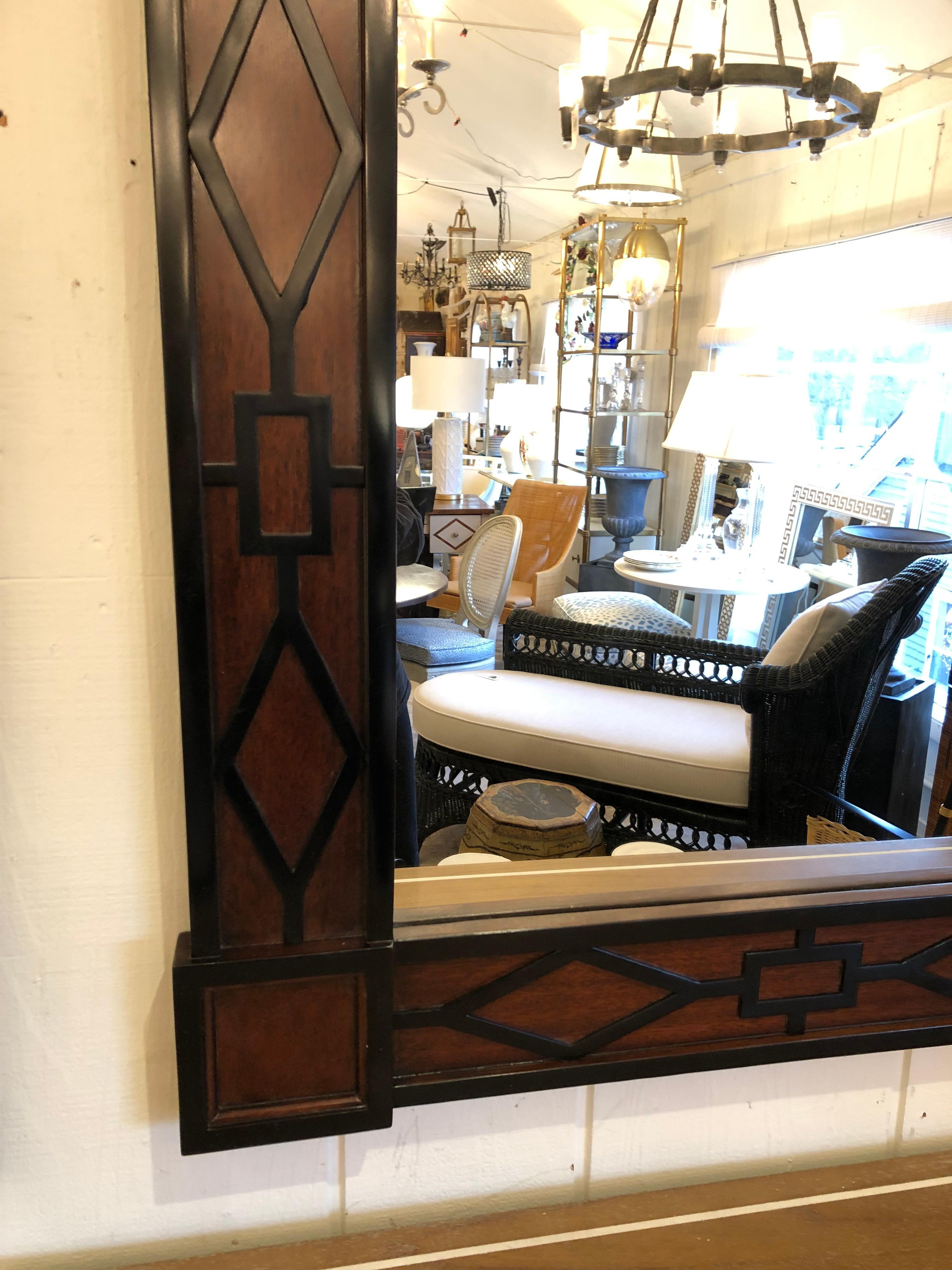 Handsome beautifully made designer mirror having rich mahogany and ebonized wood frame with a nod to Neoclassicism.