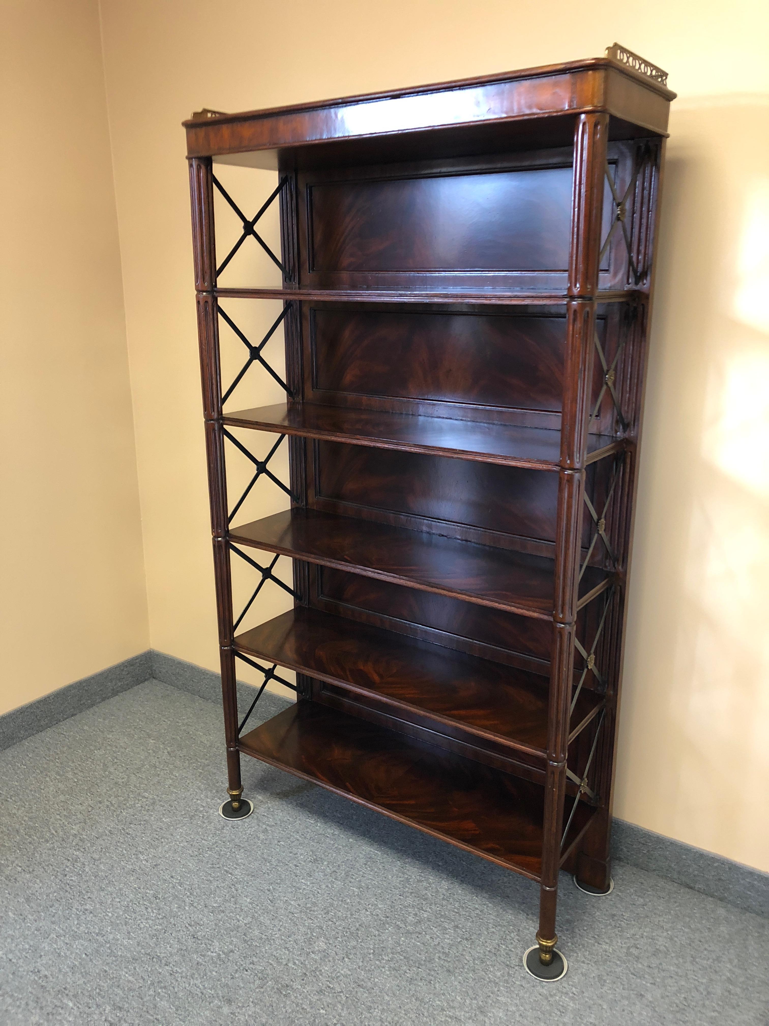 Handsome campaign style versatile flame mahogany bookshelf or étagère having 5 shelves and stylish iron X's on the sides with decorative brass medallions. Lovely brass gallery on the top edge of the étagère.
Space between shelves is 10.25 H shelves